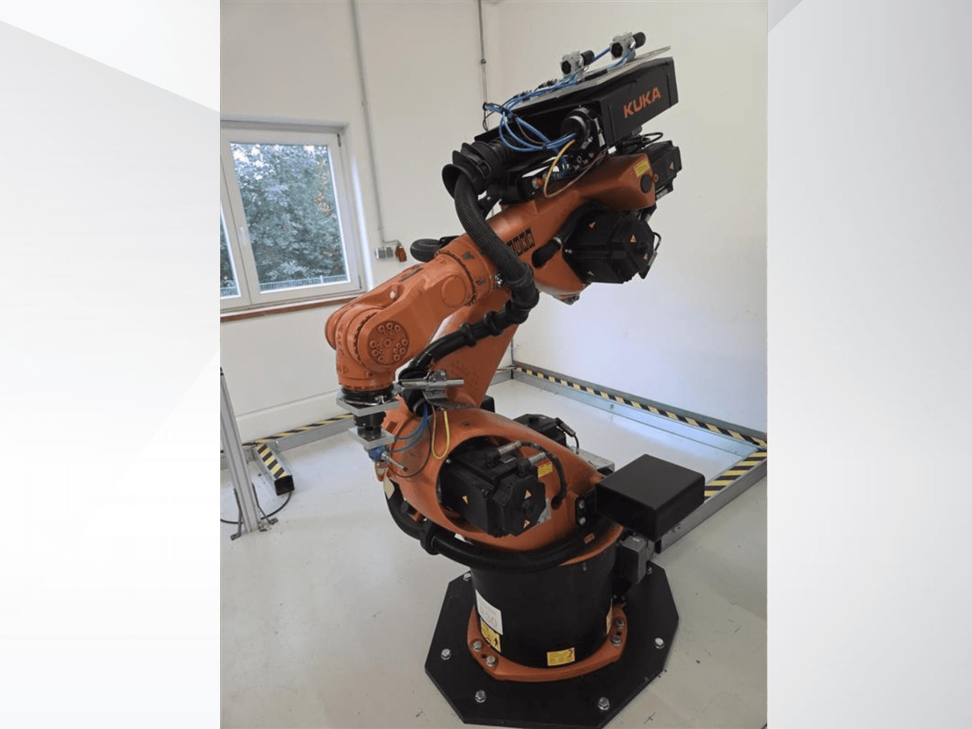KUKA KR60 HA -robottivarsi sivulta katsottuna; kuvassa näkyvät mekaaniset liitokset ja johdotus teollisuuskäyttöön tarkoitetulla alustalla.