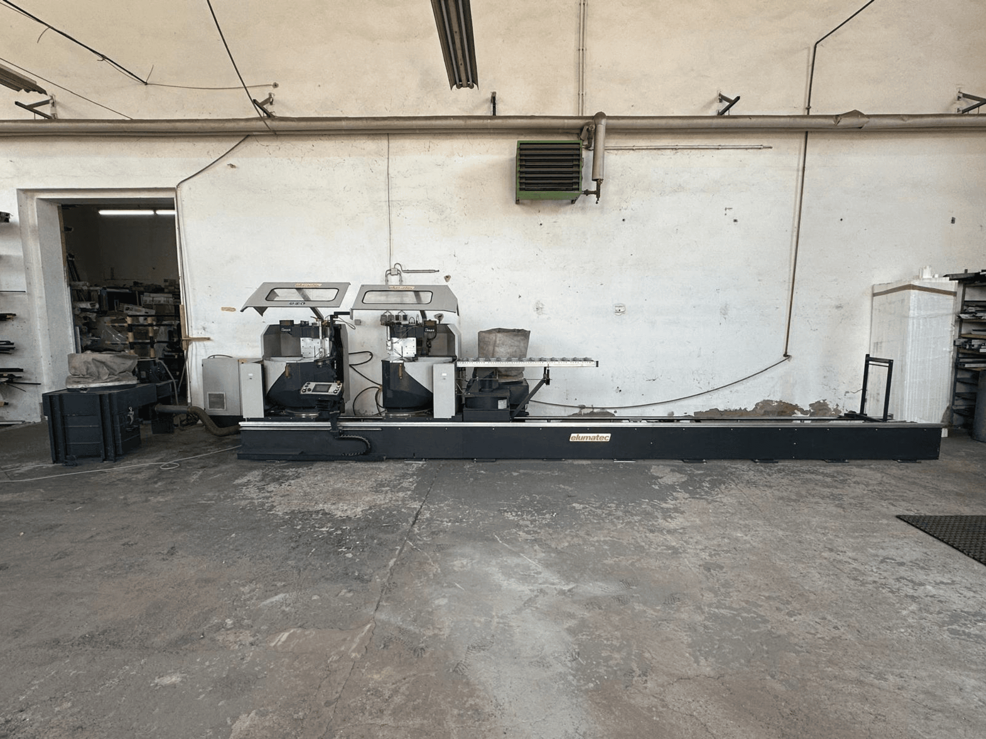 Elumatec DG 244 -metallipyörösaha työpajassa, sivukuva, jossa näkyy kaksoissahat ja hallintalaitteet tukevalla alustalla.