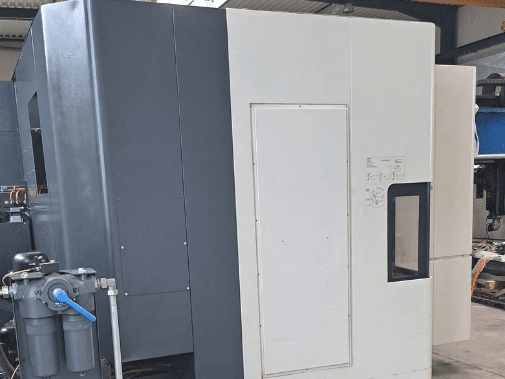DMG MORI NHX5000 -vaakakoneistuskeskus, sivukuva, jossa näkyvät ohjauspaneeli ja mekaaniset ominaisuudet.