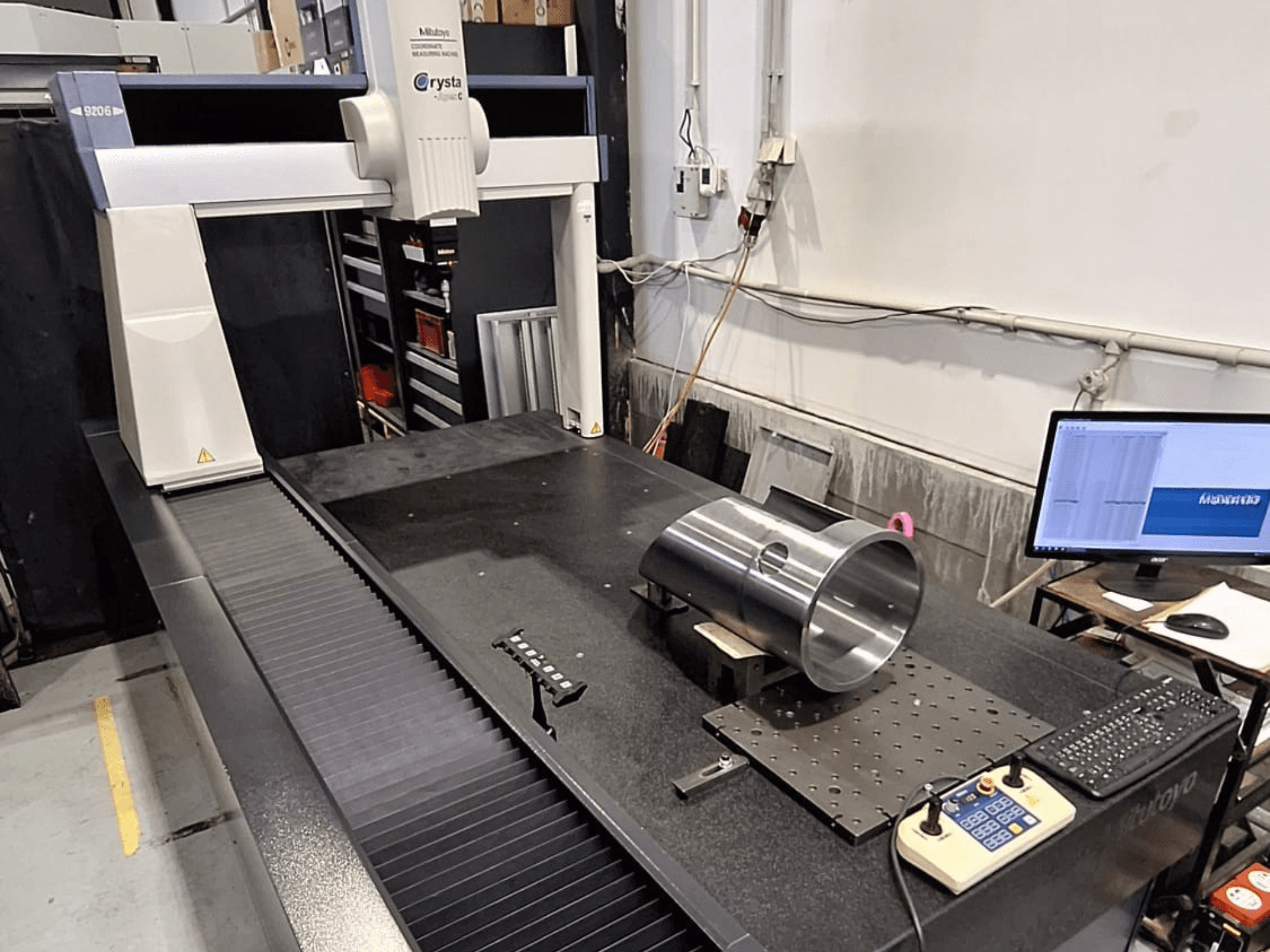 Mitutoyo Crysta-Apex C9206 CMM edestä katsottuna, mittaa lieriömäistä metalliosaa mustalla graniittipintalevyllä.