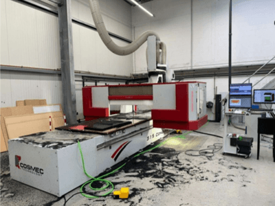 Cosmec 515 CNC-kone työpajassa, jossa on tietokonepääte, etunäkymä ja pinnalle on ripoteltu pölyä.