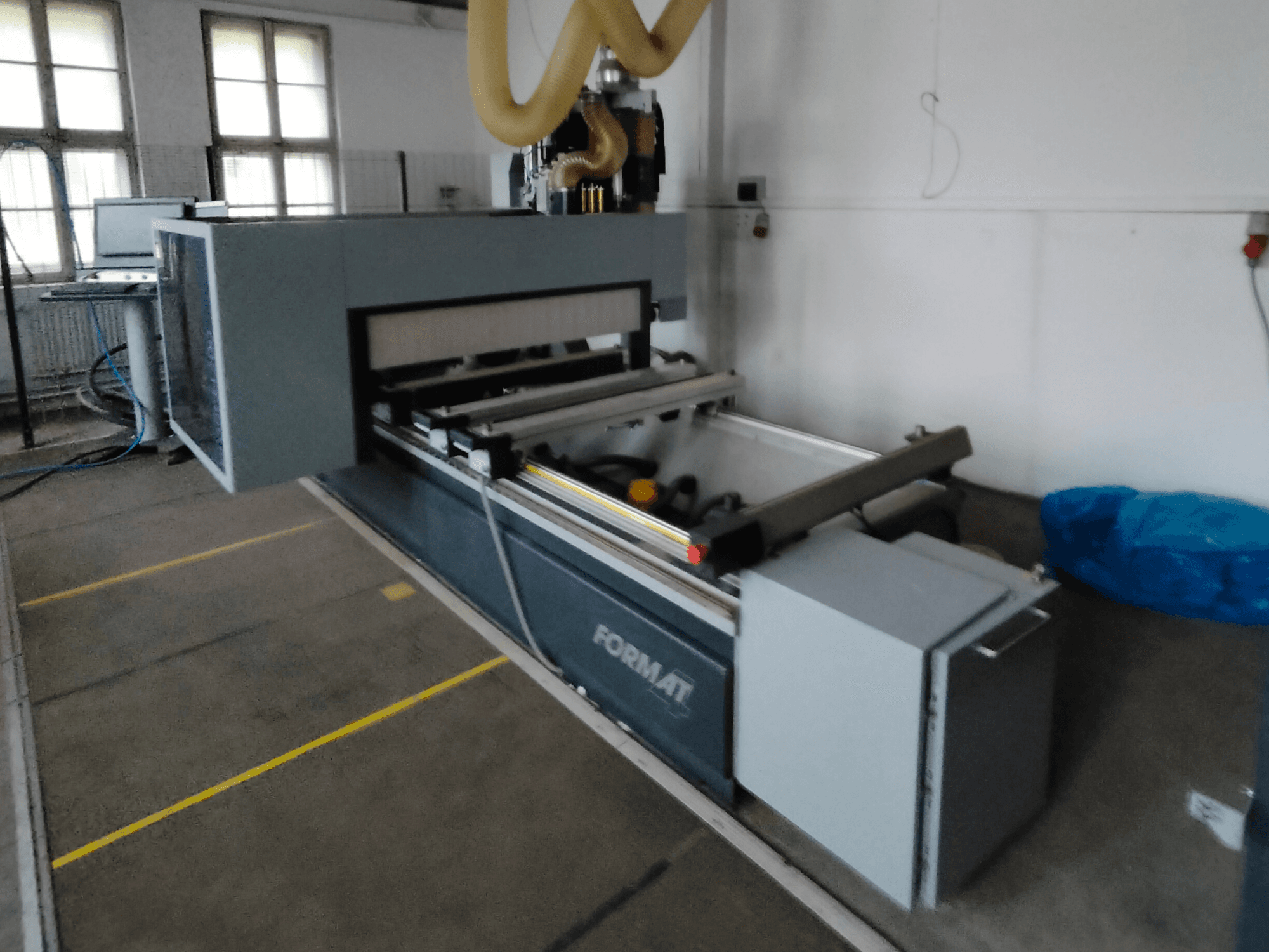Etukuva Format CNC-koneesta, jossa on harmaa runko, ohjauskiskot ja näkyvä ohjauspaneeli.