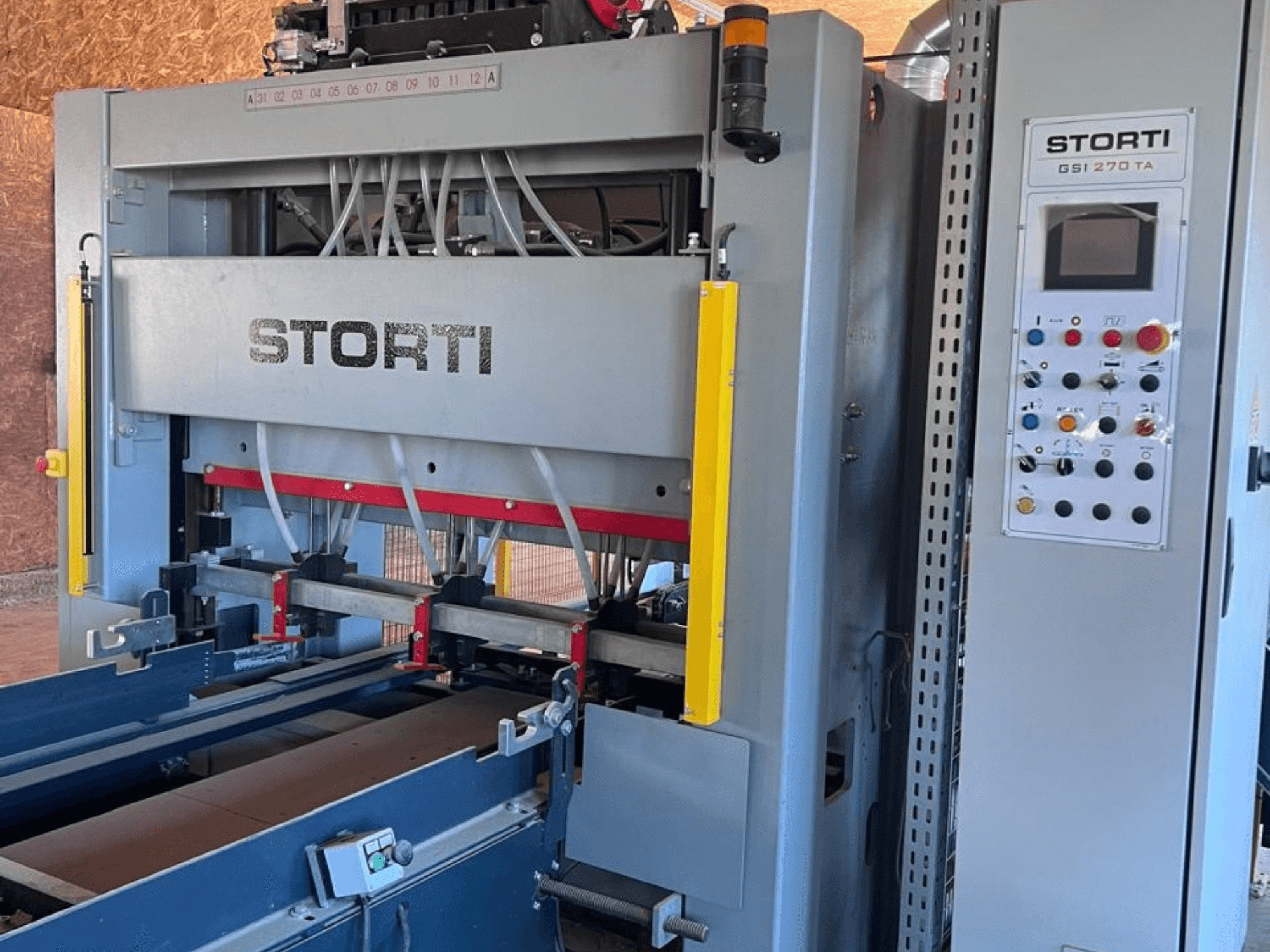 STORTI GSI 170-270 TA9 -puunjalostuslinja, etunäkymä, jossa näkyvät ohjauspaneeli ja hydraulisen puristimen mekanismit.