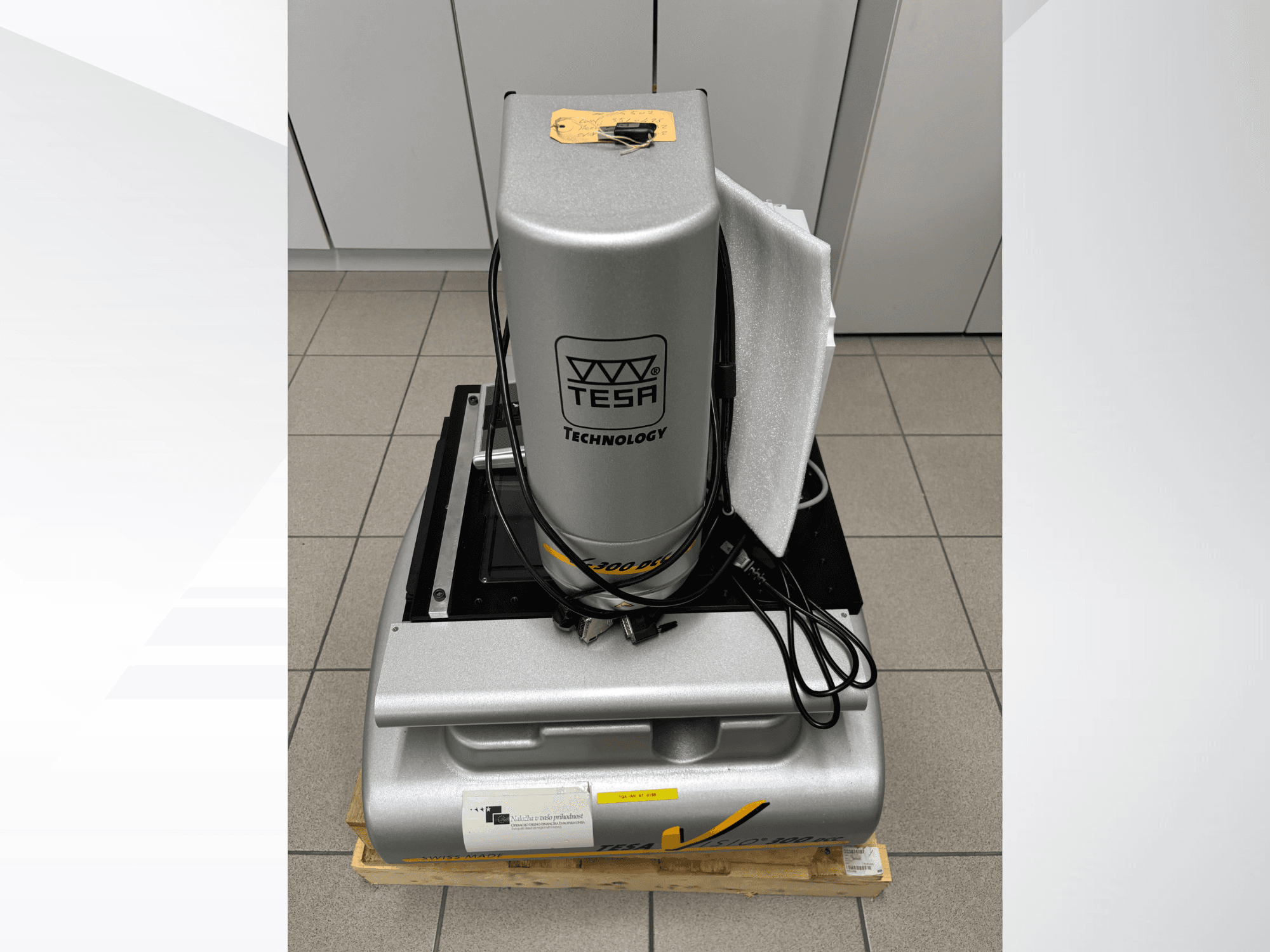 TESA Visio 300 DCC optinen mittauskone etukuvassa kaapelien kanssa puulavalla, suojapakkaus näkyvissä.