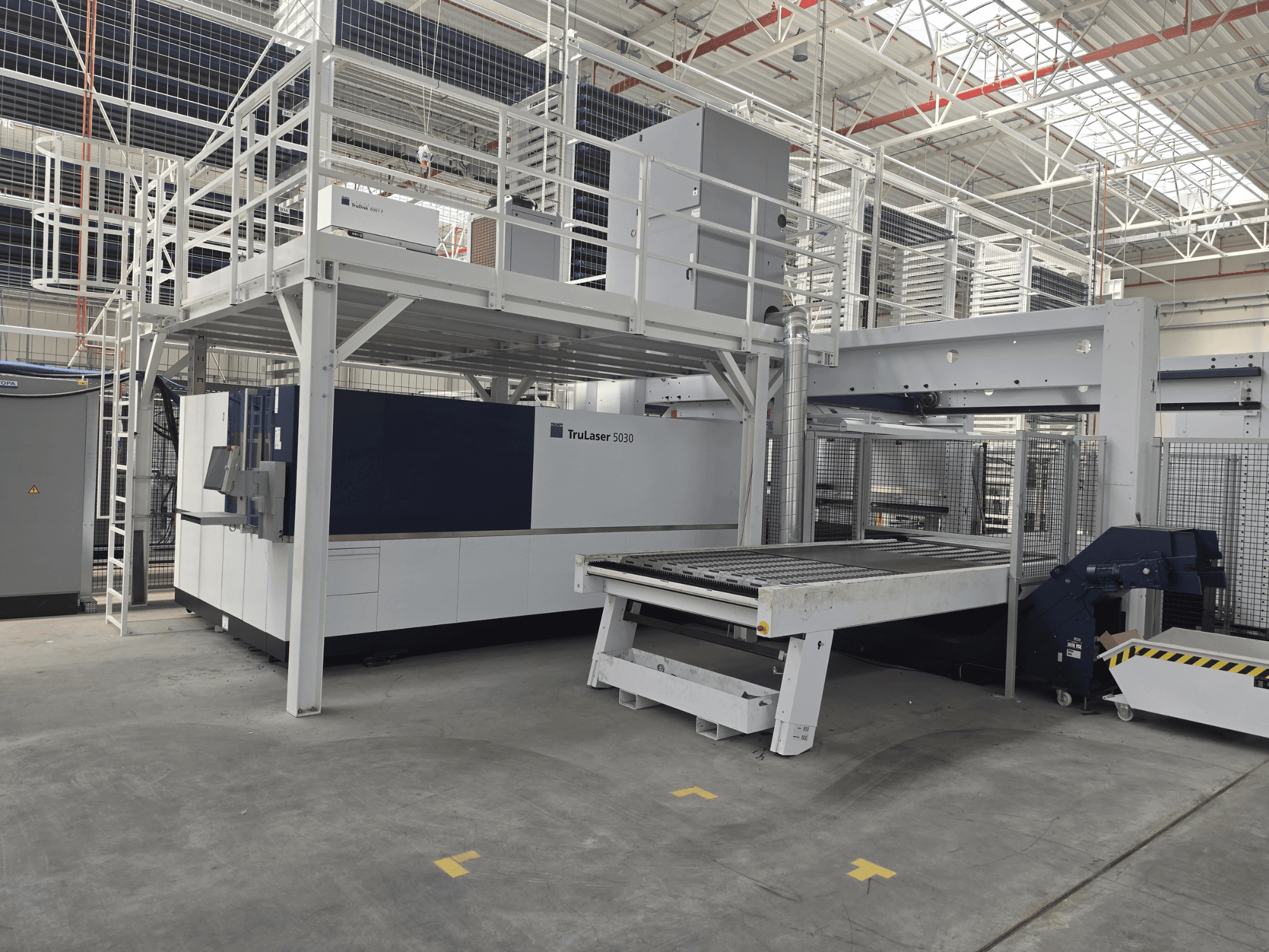 TRUMPF TruLaser 5030 fiber L76 FMC -kone työpajassa, etunäkymä, jossa näkyy leikkausalue sekä lastaus- ja purkumekanismi.
