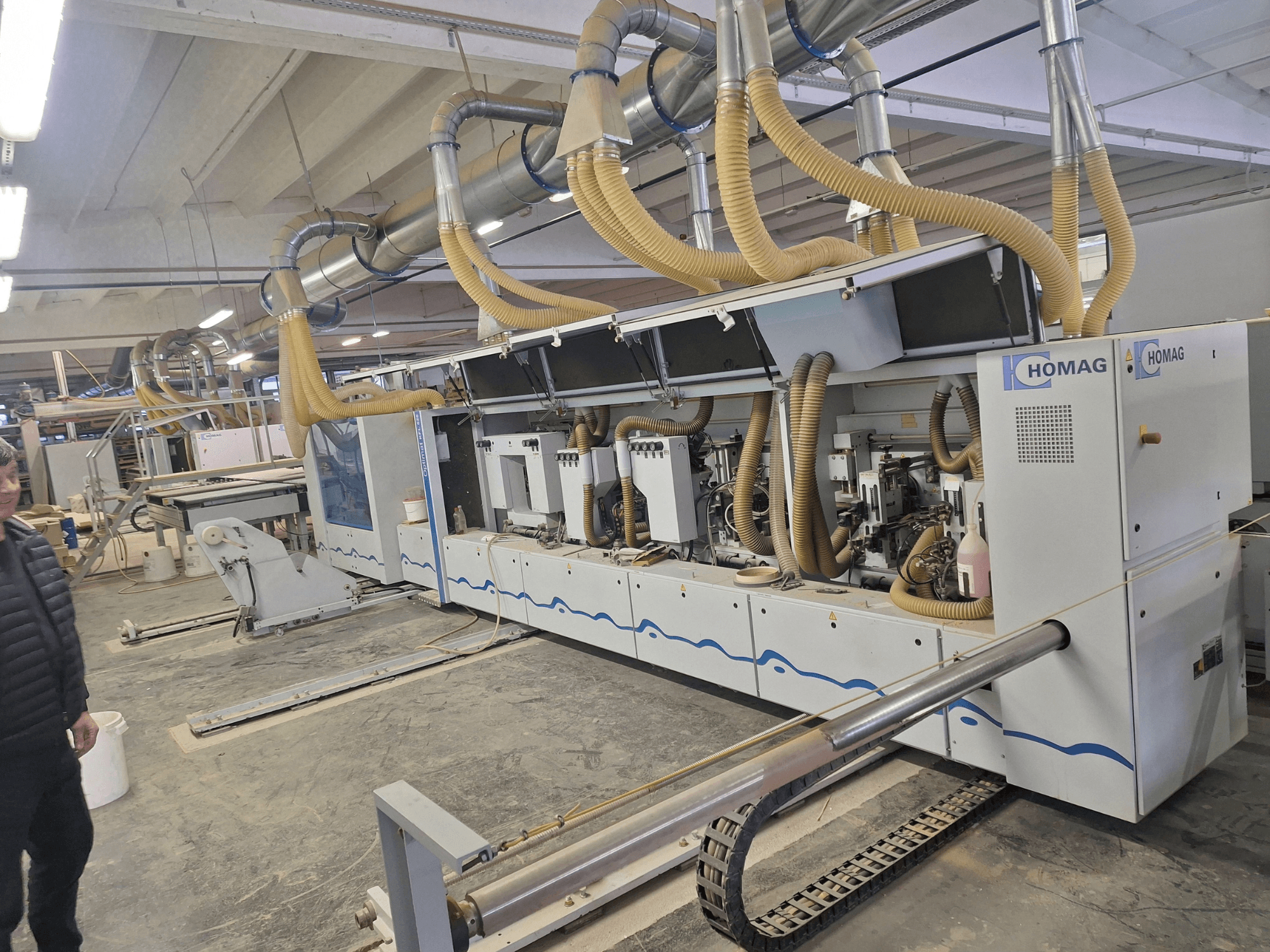 HOMAG-puuntyöstökone tehdasympäristössä, etukuva, jossa näkyy useita karoja ja pölynpoistojärjestelmä.