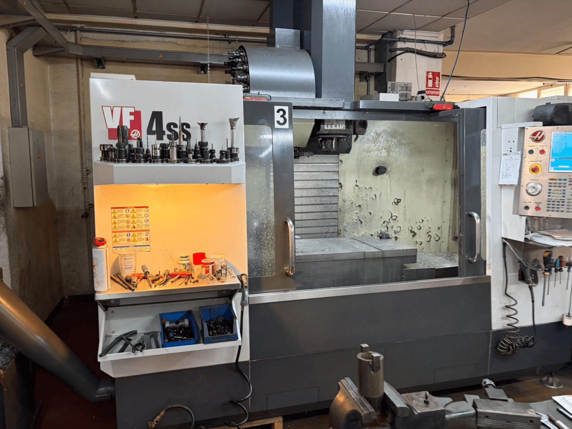 HAAS VP 4SS -pystykoneistuskeskus, etunäkymä, jossa näkyvät työkaluvarasto, ohjauspaneeli sekä työstöalue ja sen yksityiskohdat.