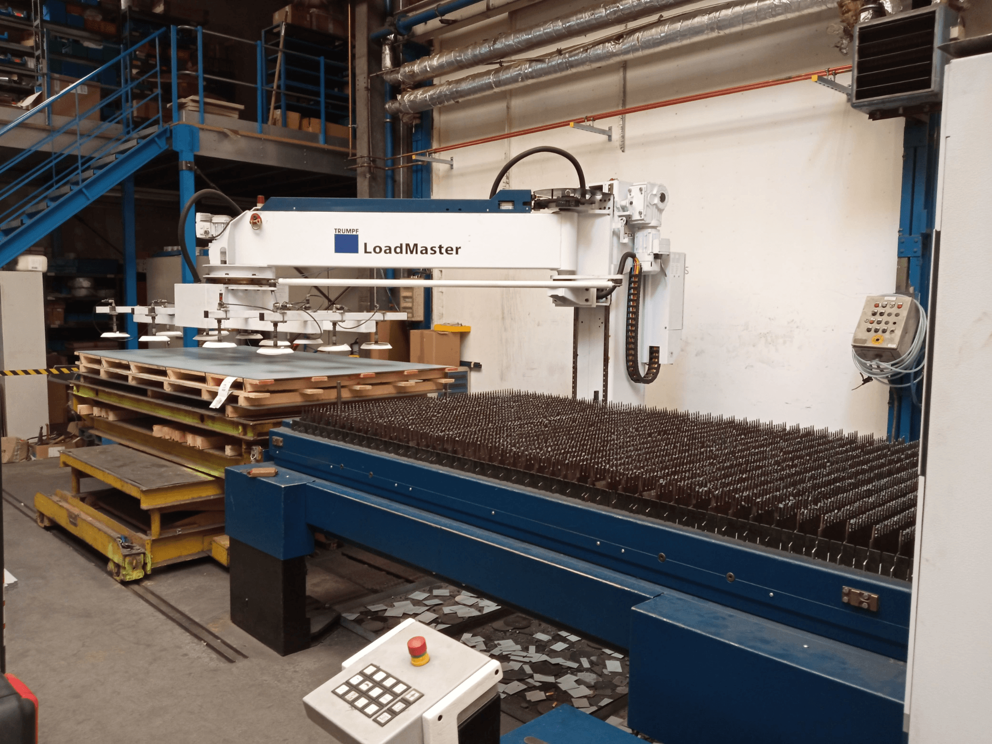 TRUMPF TruLaser 3030 CO₂-laserleikkauskone sivulta katsottuna, kuvassa LoadMaster-laite ja materiaalipaletteja.