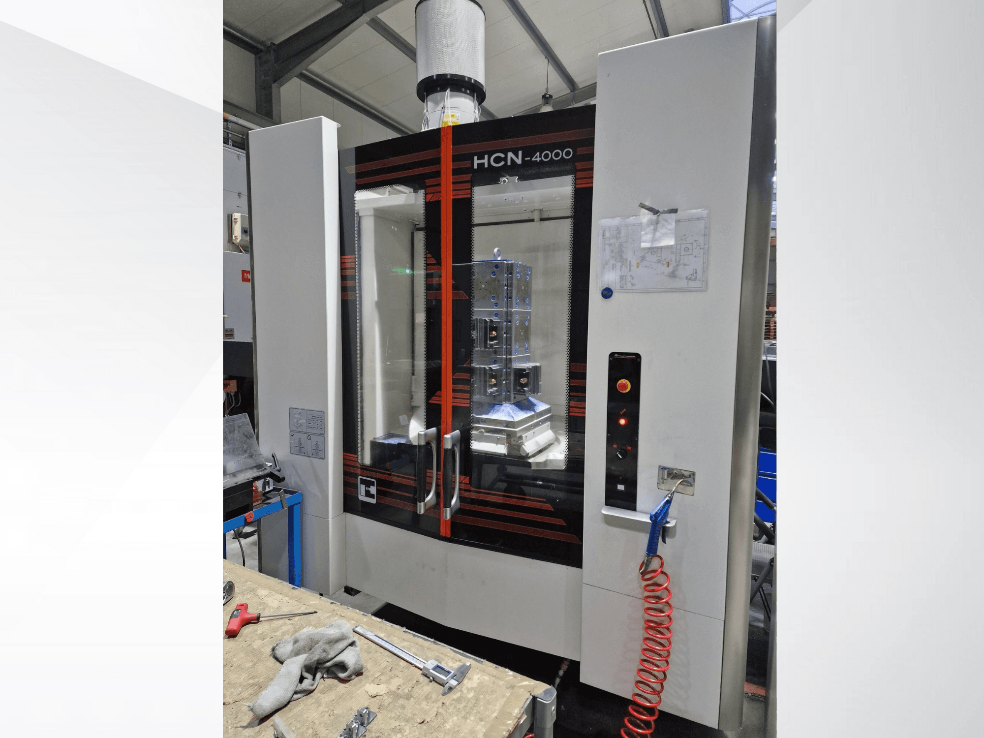 HCN-4000 CNC-kone etukuvassa, jossa on lasipaneeli, ohjauspaneeli painikkeilla ja piirustuskartta liitteenä.