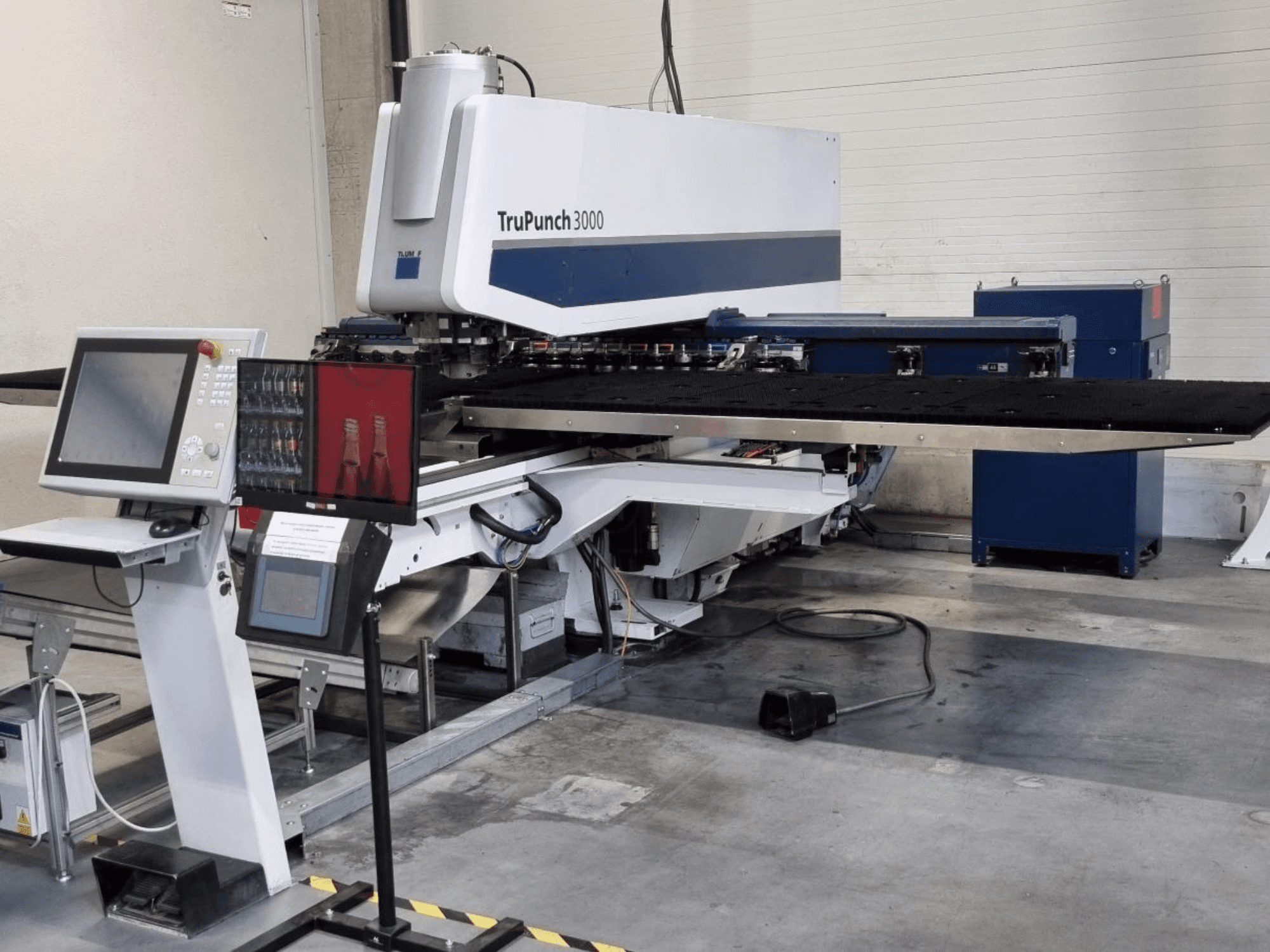 CNC-lävistyskone TRUMPF TruPunch 3000 edestä katsottuna, ohjauspaneeli ja suuri lävistyspöytä näkyvissä.
