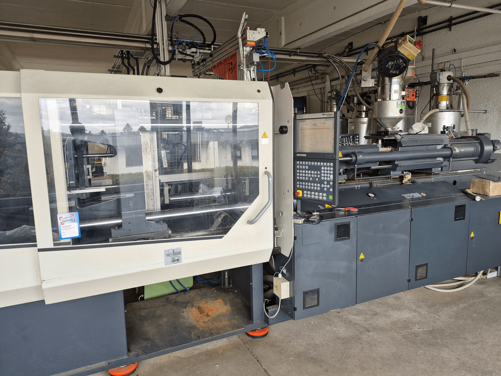 Hydraulinen ruiskuvalukone, SUMITOMO SHI DEMAG Systec 210/580-1450, etunäkymä ohjauspaneelilla ja näkyvillä olevilla osilla.