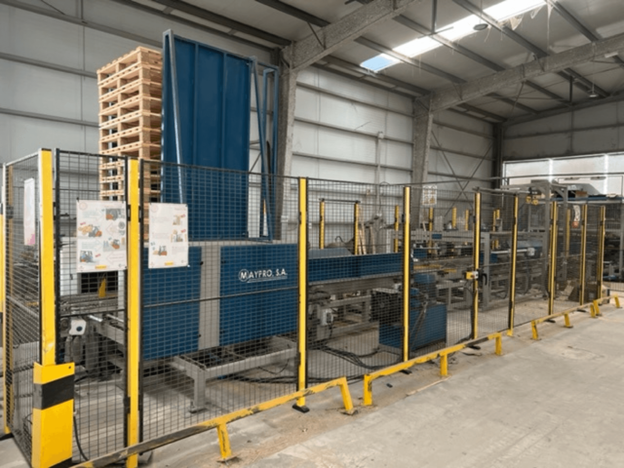 Maypro S.A.:n teollinen kuormalavapakkauskone varastossa, jossa on turvaverkko ja käyttöohjaimet, sivukuva.