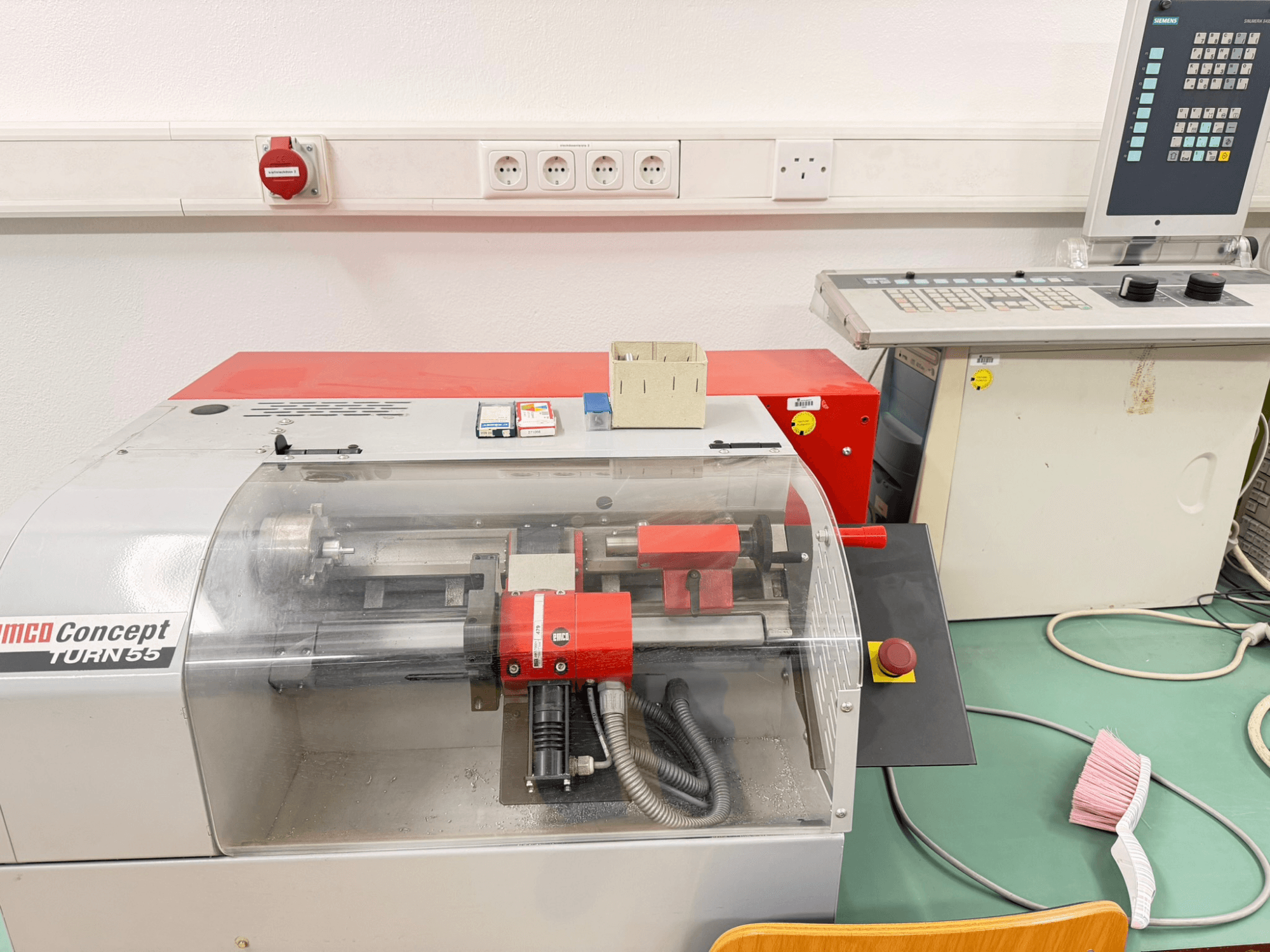 EMCO Concept Turn 55 vaakasuora sorvauskone, jossa on punainen ja harmaa ulkokuori, etukuva, jossa näkyvät hallintalaitteet ja työskentelyalue.