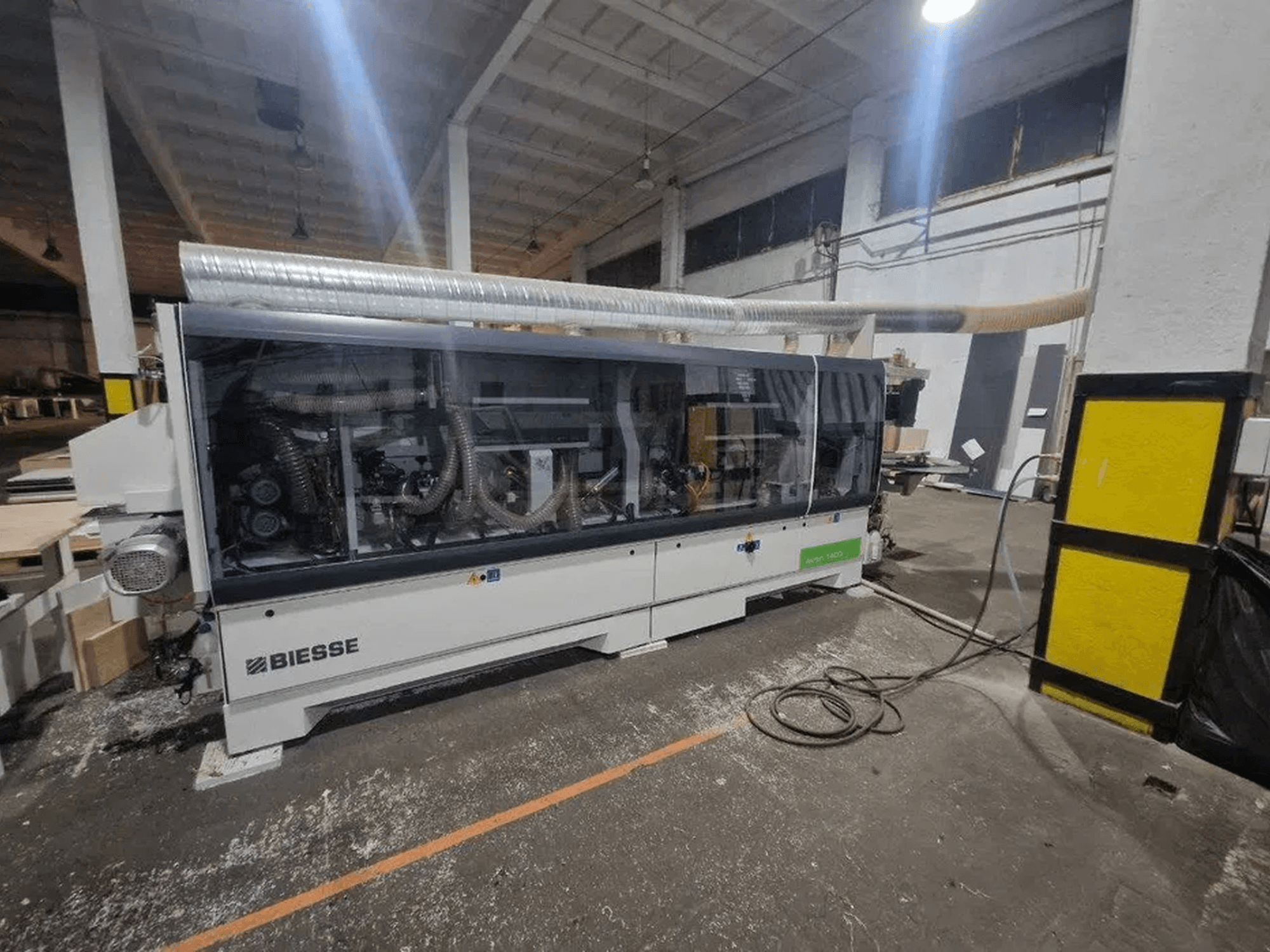 BIESSE Akron 1440 A -reunakone työpajassa, jossa on läpinäkyvä suojakansi ja näkyvät koneen osat.
