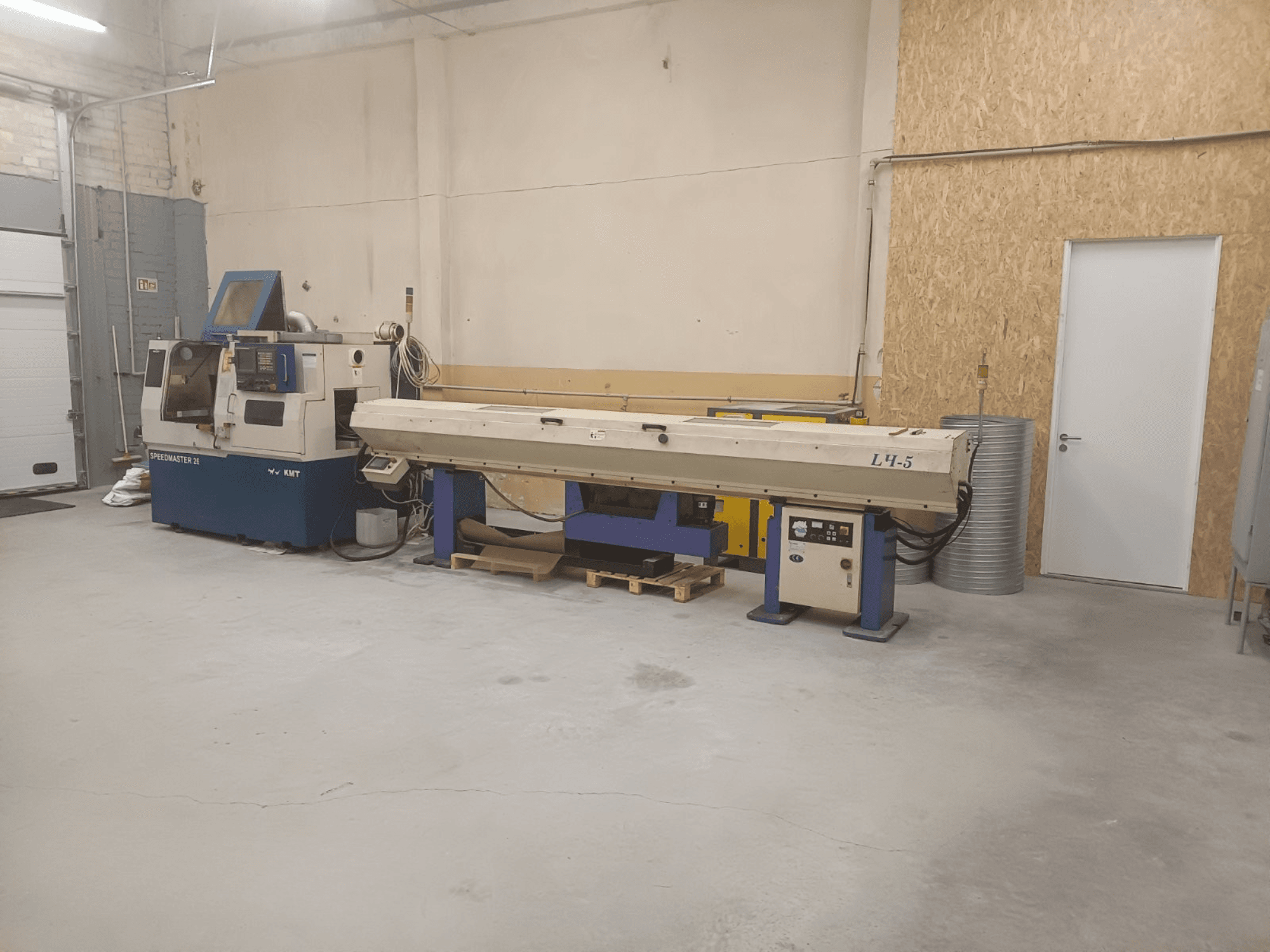 Teollisuustyöpaja, jossa on KMT Speedmaster 34 -kone ja L4.5, edestä katsottuna, näkyvissä hallintalaitteet ja koneet.