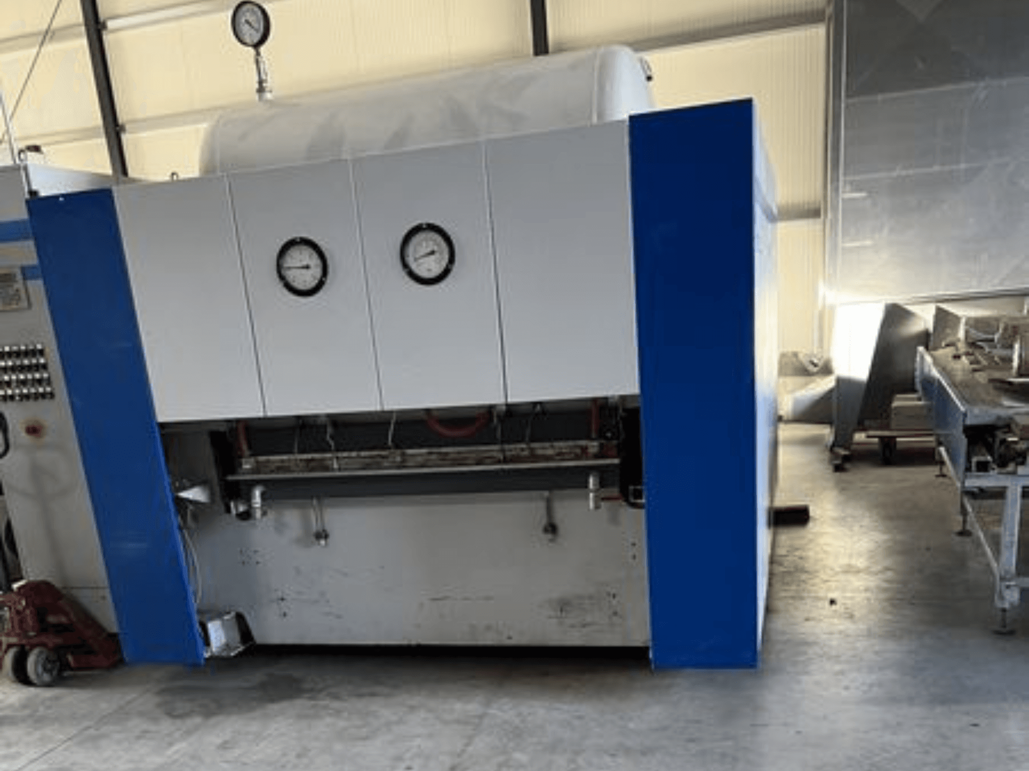 Sinivalkoinen teollisuuskone, jossa on kaksi painemittaria, etukuva, jossa on ohjauspaneeli ja viereisiä laitteita.