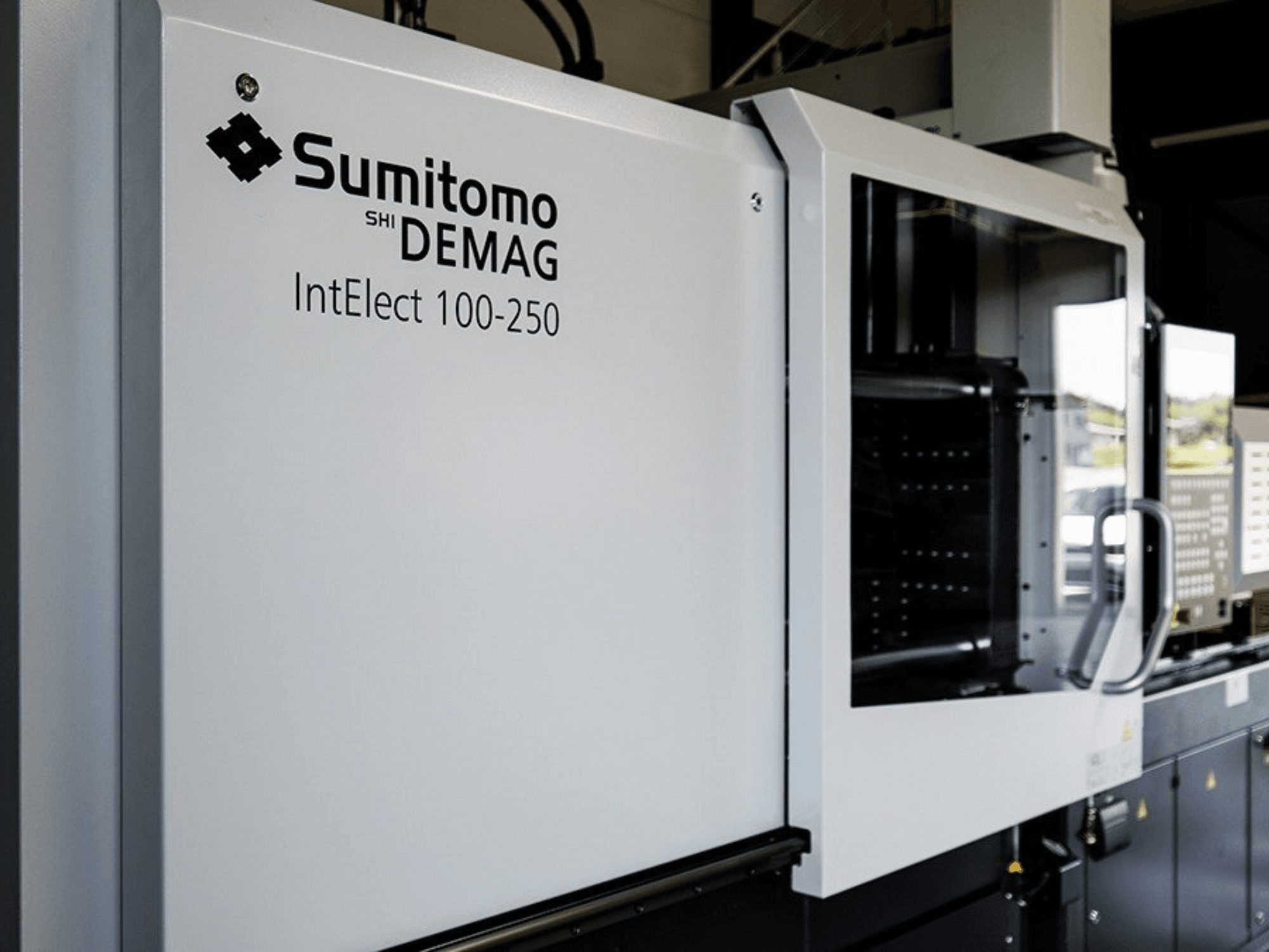 SUMITOMO SHI DEMAG IntElect 100/250 -sähköisen ruiskuvalukoneen etunäkymä, jossa näkyvät ohjauspaneeli ja turvalaitteet.