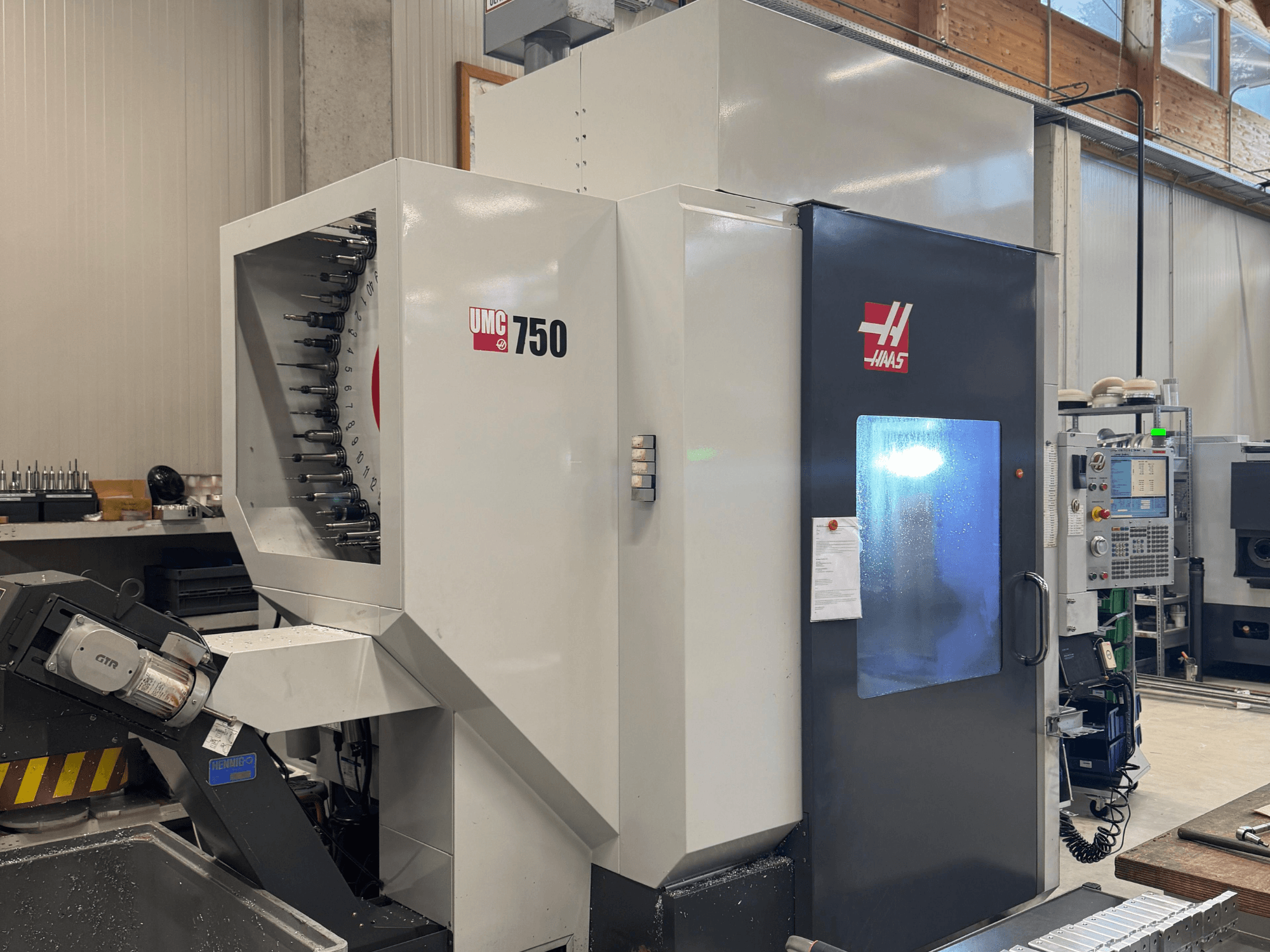 Haas UMC 750 -työstökeskus, etukuva, jossa näkyy työkalunpidin ja ohjauspaneeli työpajassa.
