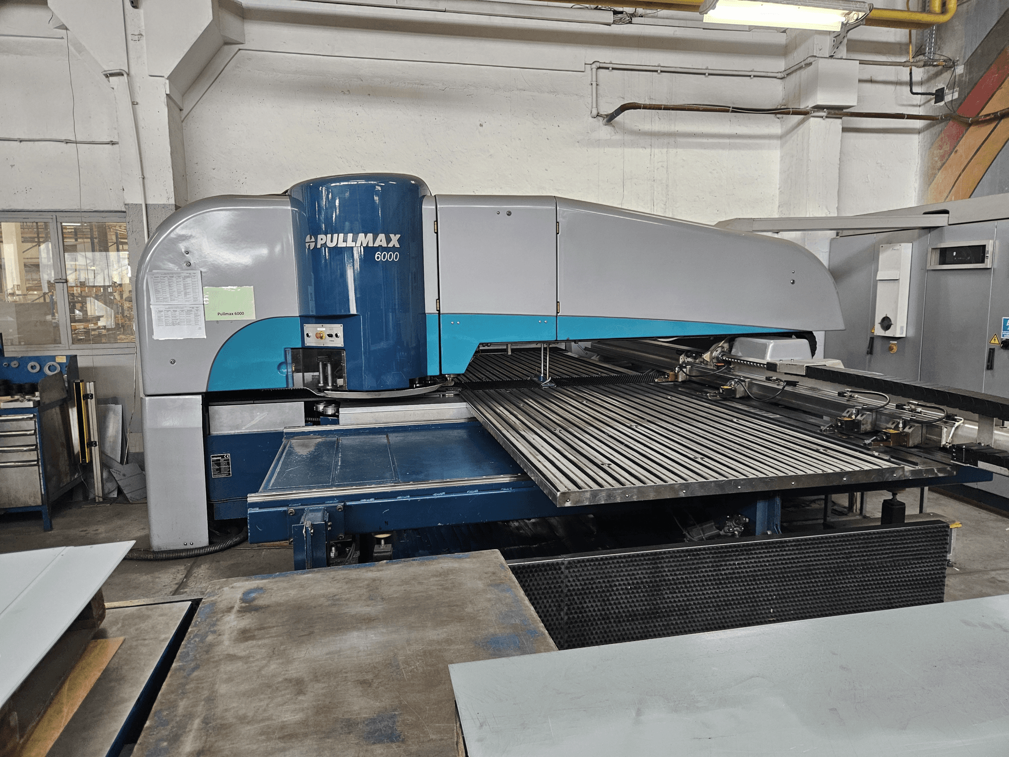 Pullmax 6000 CNC-lyöntikoneen etunäkymä, jossa esitellään sen suuri litteä alusta ja metallirunko työpajan ympäristössä.