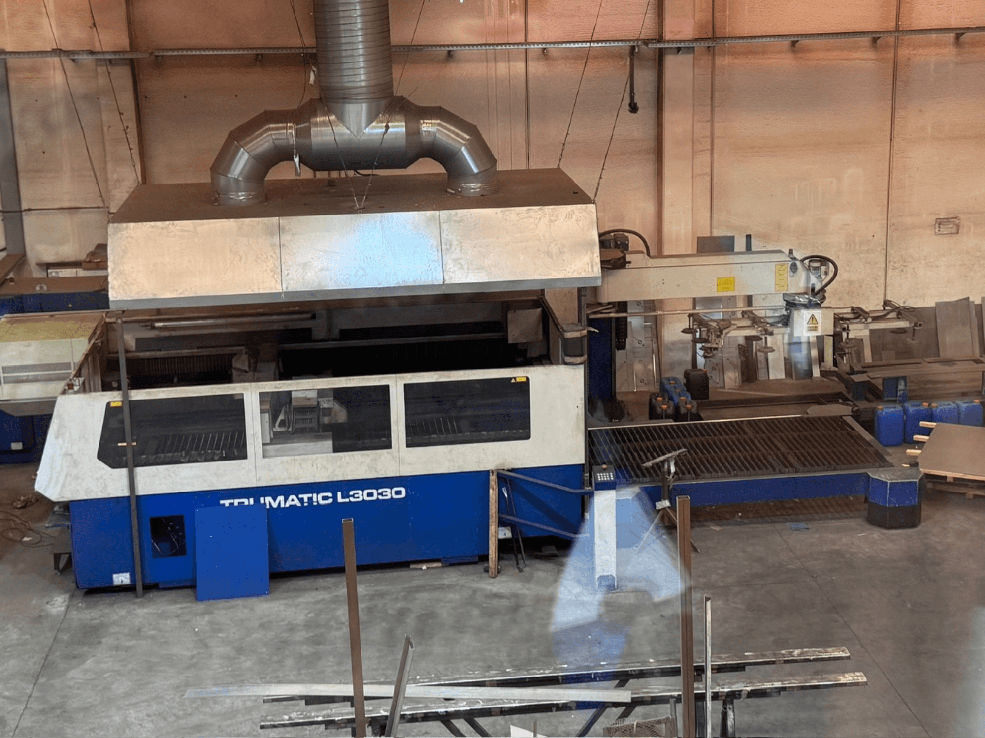 TRUMPF TRUMATIC L3030 -CO2-laserleikkauskone työpajassa, etunäkymä, jossa näkyvät ohjauspaneeli ja leikkausalusta.
