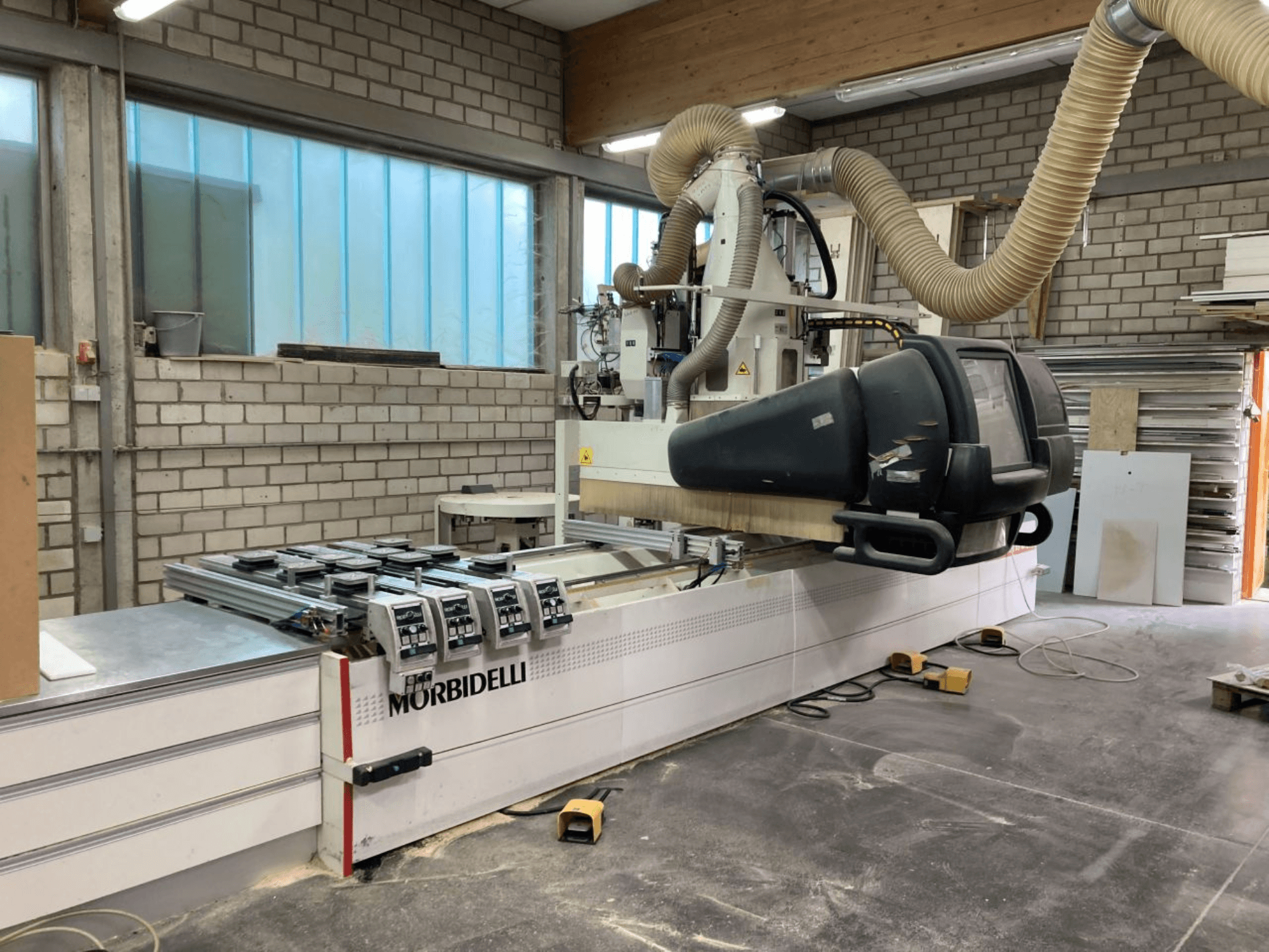 MORBIDELLI CNC-kone työpajassa, etukuva, jossa ohjauspaneeli, pölynpoistojärjestelmä ja puukappale paikallaan.