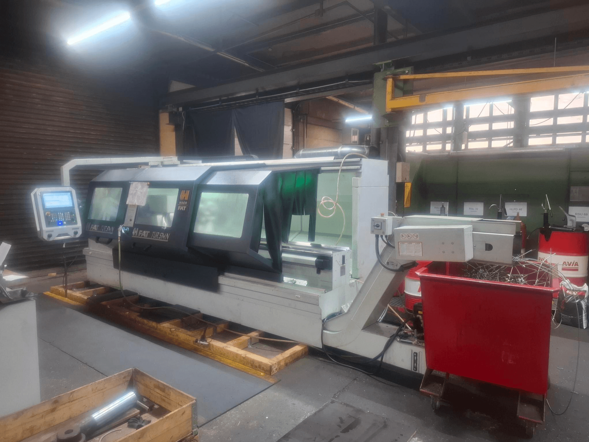 Etukuva FAT Tursan CNC-koneesta ja ohjauspaneelista, joka on sijoitettu puulavoille työpajassa.
