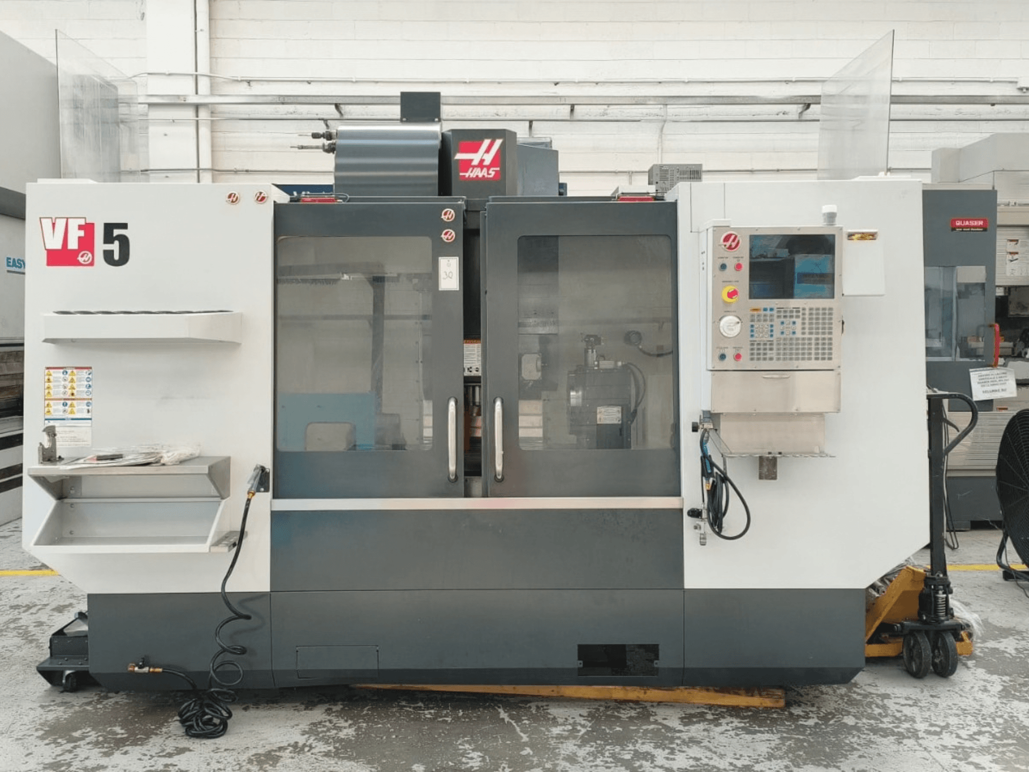 HAAS VF 5/40 -pystykoneistuskeskus edestä katsottuna, ohjauspaneeli ja lasiovet näkyvissä.