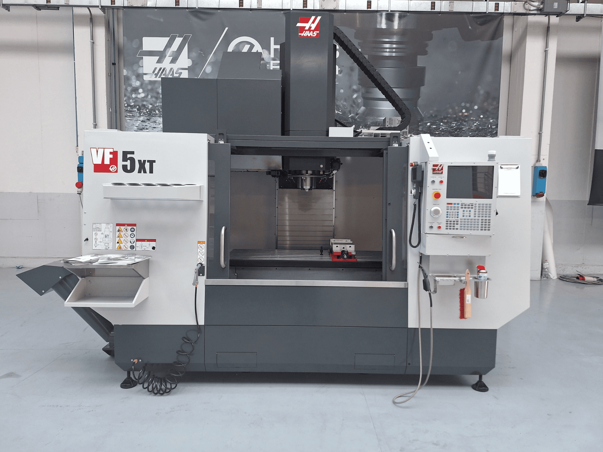 HAAS VF-5/50XT -pystykoneistuskeskus, etunäkymä, jossa näkyvät ohjauspaneeli, karan alue ja työkalujen säilytystila.