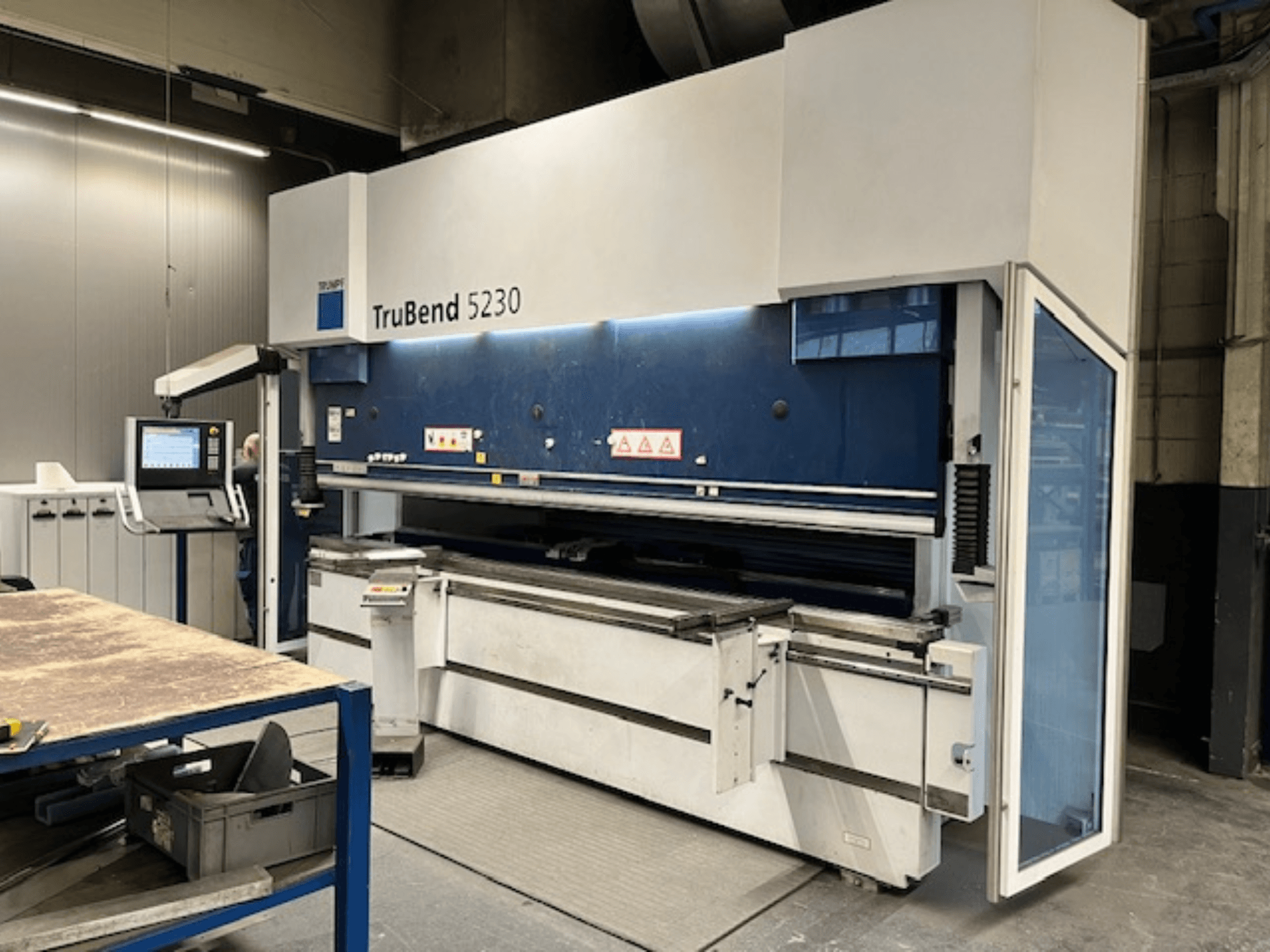 TruBend 5230 -taivutuskone teollisuusympäristössä; etukuva, jossa näkyy ohjauspaneeli, turvaominaisuudet ja työpöytä.