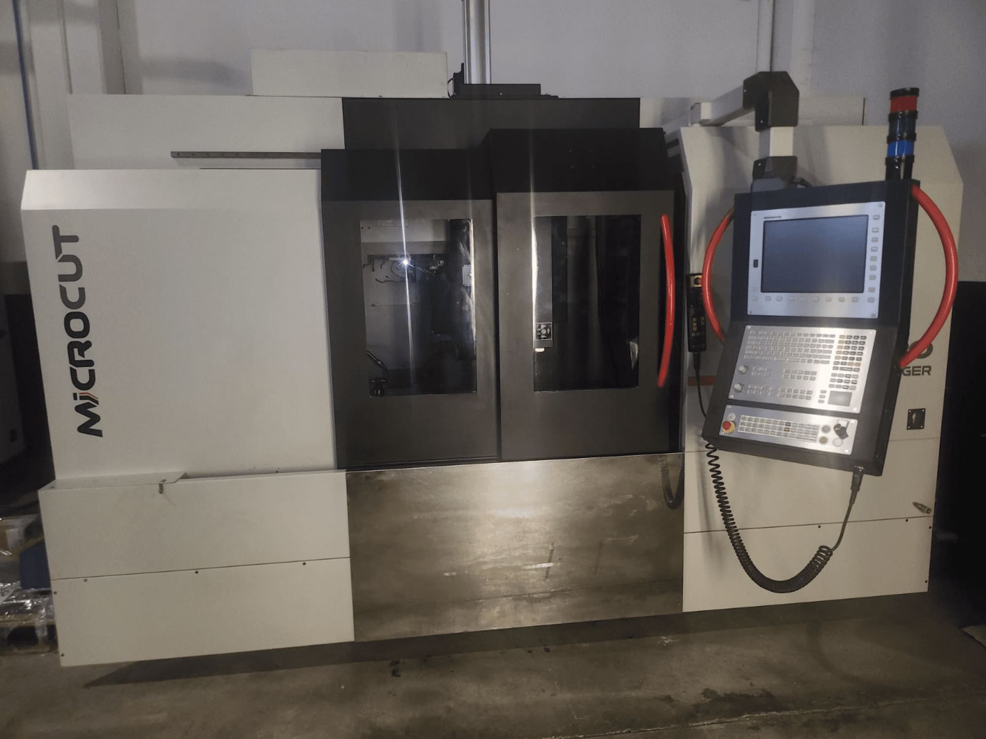 Microcut CNC-kone edestä katsottuna; siinä on ohjauspaneeli, kaksi ikkunaa, teollinen muotoilu ja metallinen viimeistely.