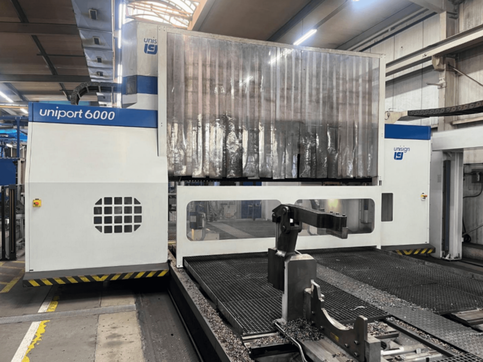 Gantry-jyrsin Unisign uniport 6000, etukuva, jossa näkyy koneen rakenne ja leikkausalue, jossa on metallilastuja.