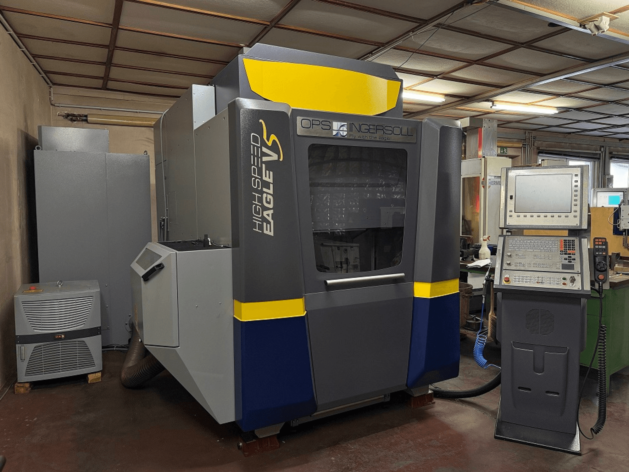 OPS Ingersollin suurnopeus Eagle V -kone, sivukuva, ohjauspaneeli ja viereiset laitteet teollisuusympäristössä.