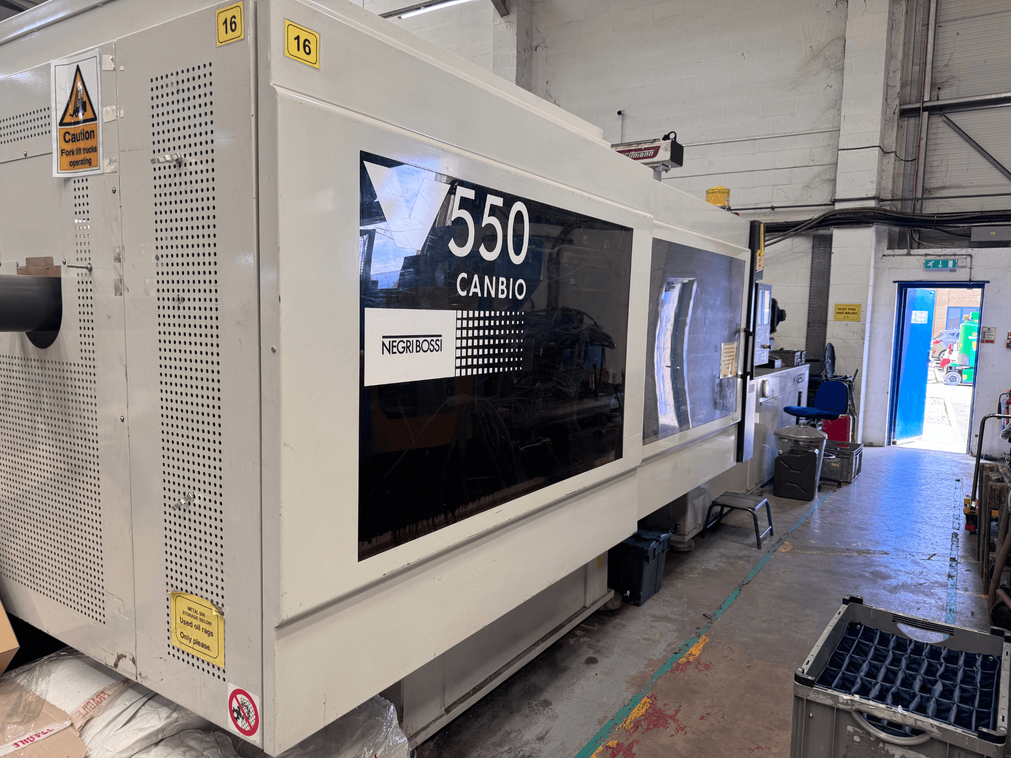 Negri Bossi 5500H-4250 -hydraulinen ruiskuvalukone, etunäkymä, jossa näkyvät ohjauspaneeli ja varoitusmerkit.