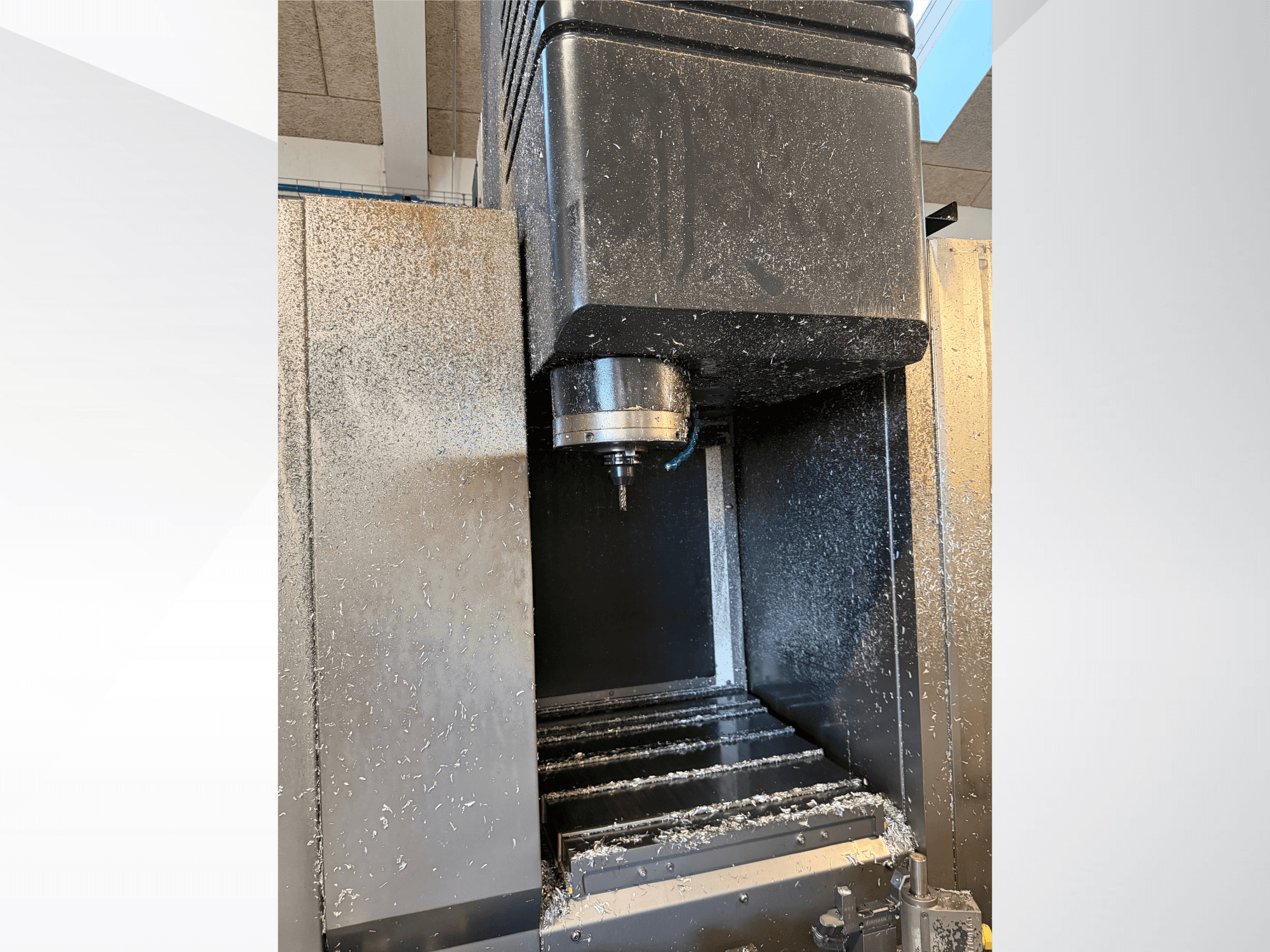 Mazak VTC 300C II -pystykoneistuskeskus, etunäkymä, jossa näkyvät kara ja koneistusprosessissa syntyneet lastut.