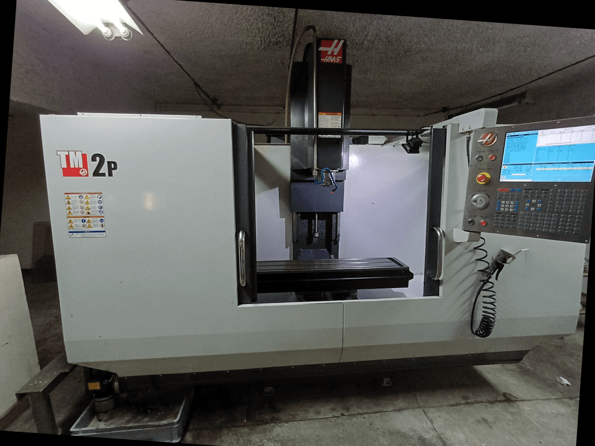 HAAS TM-2P -pystytyöstökeskus, etukuva, jossa näkyy ohjauspaneeli, karanpää ja koneen sänky.