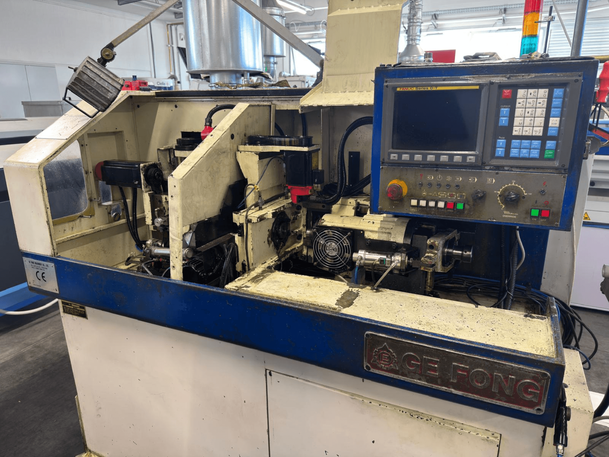 GE FONG -teollisuuskone etukuvassa, jossa näkyvät sisäiset komponentit, ohjauspaneeli ja käyttöosat.