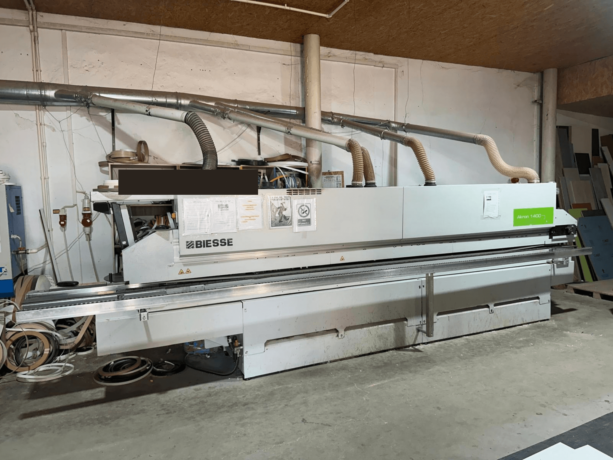 BIESSE AKRON 1440 A -reunakone, etunäkymä, jossa näkyvät käyttöpaneeli ja pölynpoistokomponentit työpajaympäristössä.