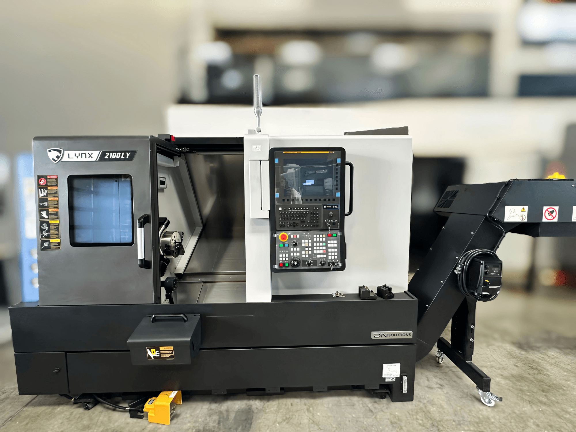 Vaakasuuntainen sorvauskone DN SOLUTIONS LYNX 2100LYB, etukuva, jossa on ohjauspaneeli ja avoin ovi, joka paljastaa sisätilat.