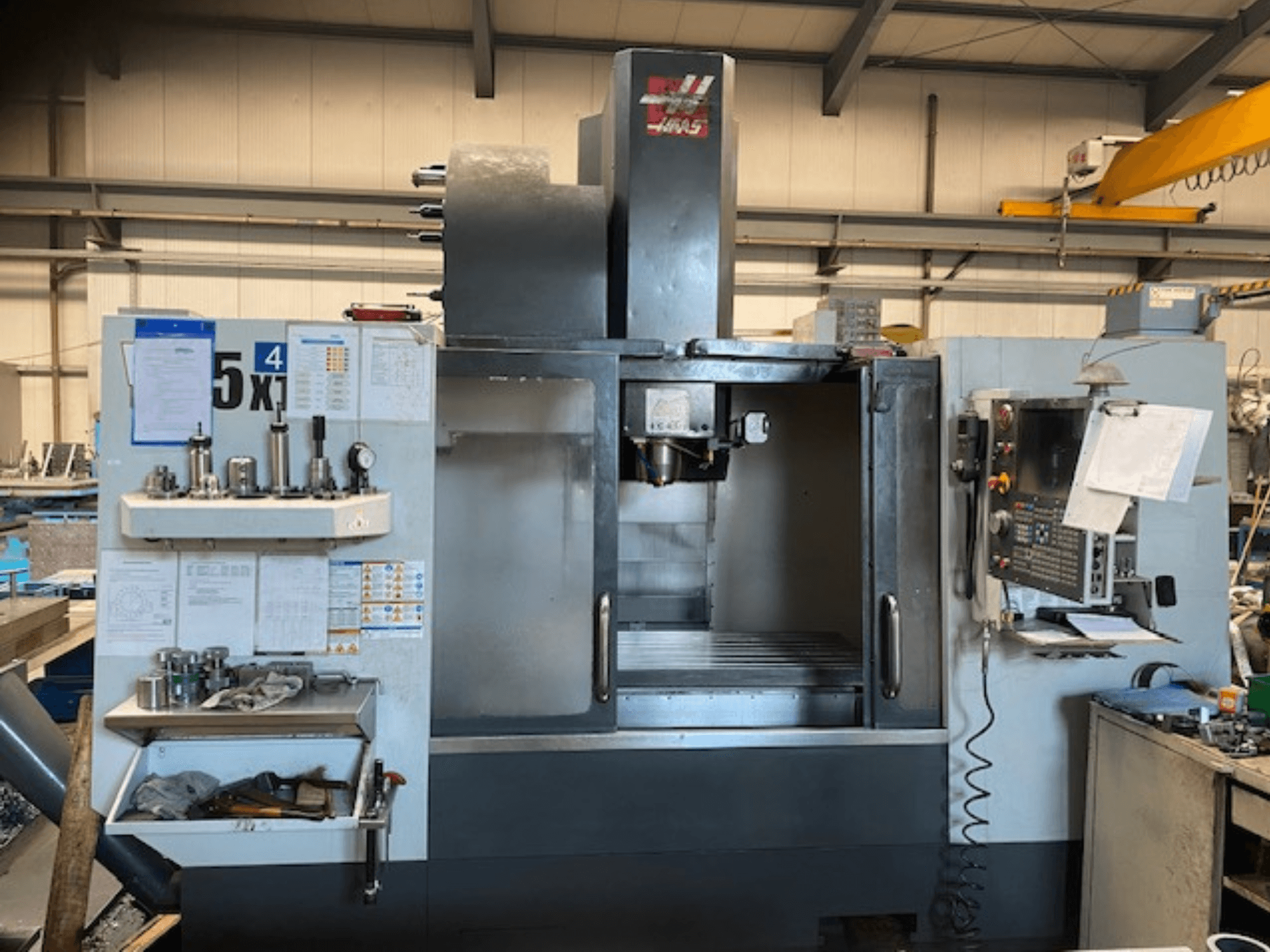 Haas VF-5 -pystytyöstökeskus, etukuva, jossa näkyy ohjauspaneeli, työkalujen säilytys ja karan alue.