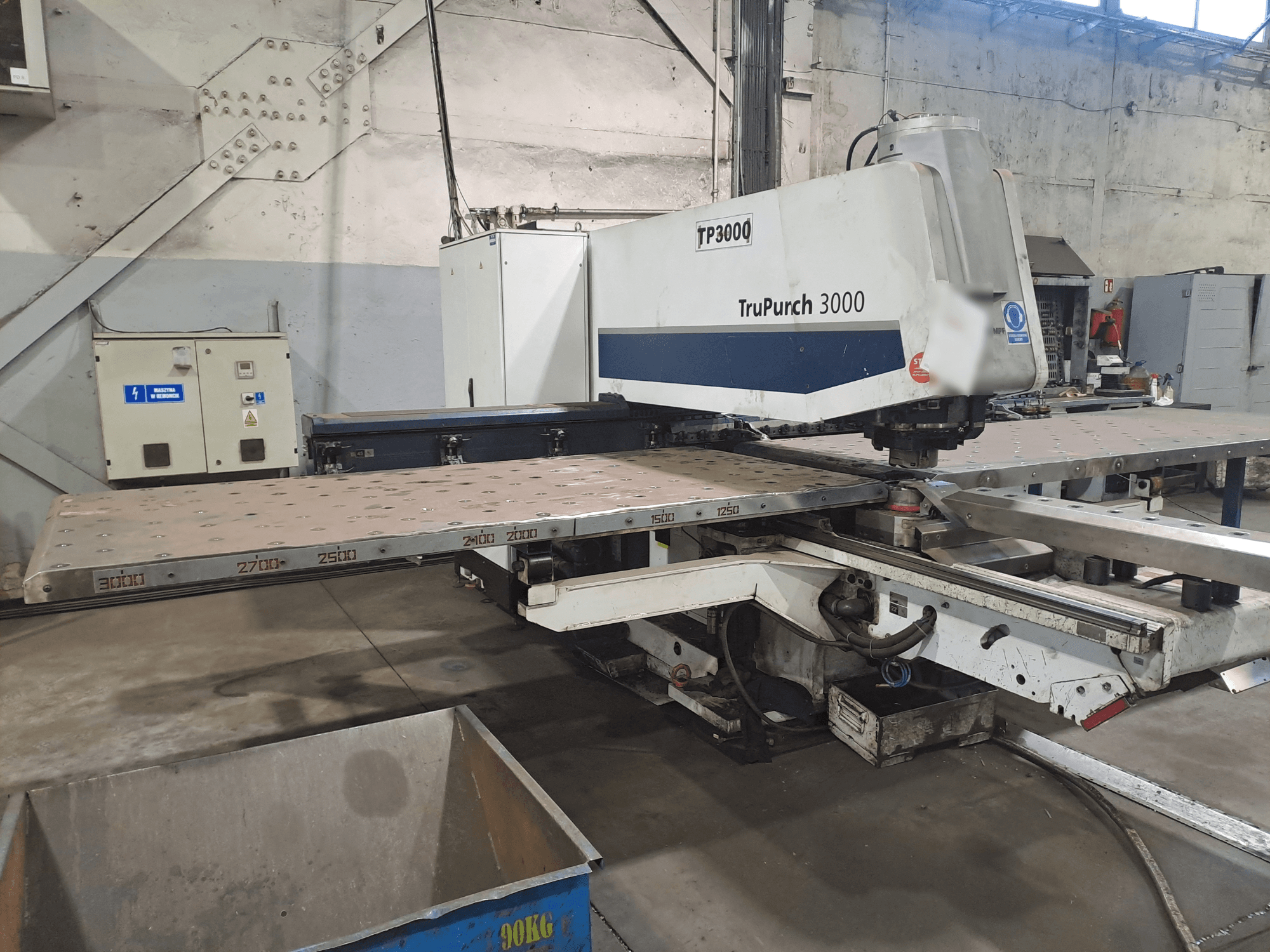 TruPunch 3000 CNC-kone edestäpäin, suuri metallilevy ja mittausmerkinnät teollisuusympäristössä.