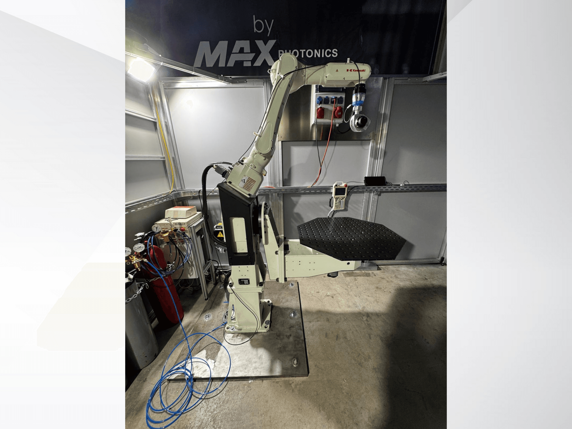 Max Photonicsin robottikäsivarsi, etukuva, jossa on musta rei'itetty alusta ja ohjauspaneeli mittareineen ja kaapeleineen.