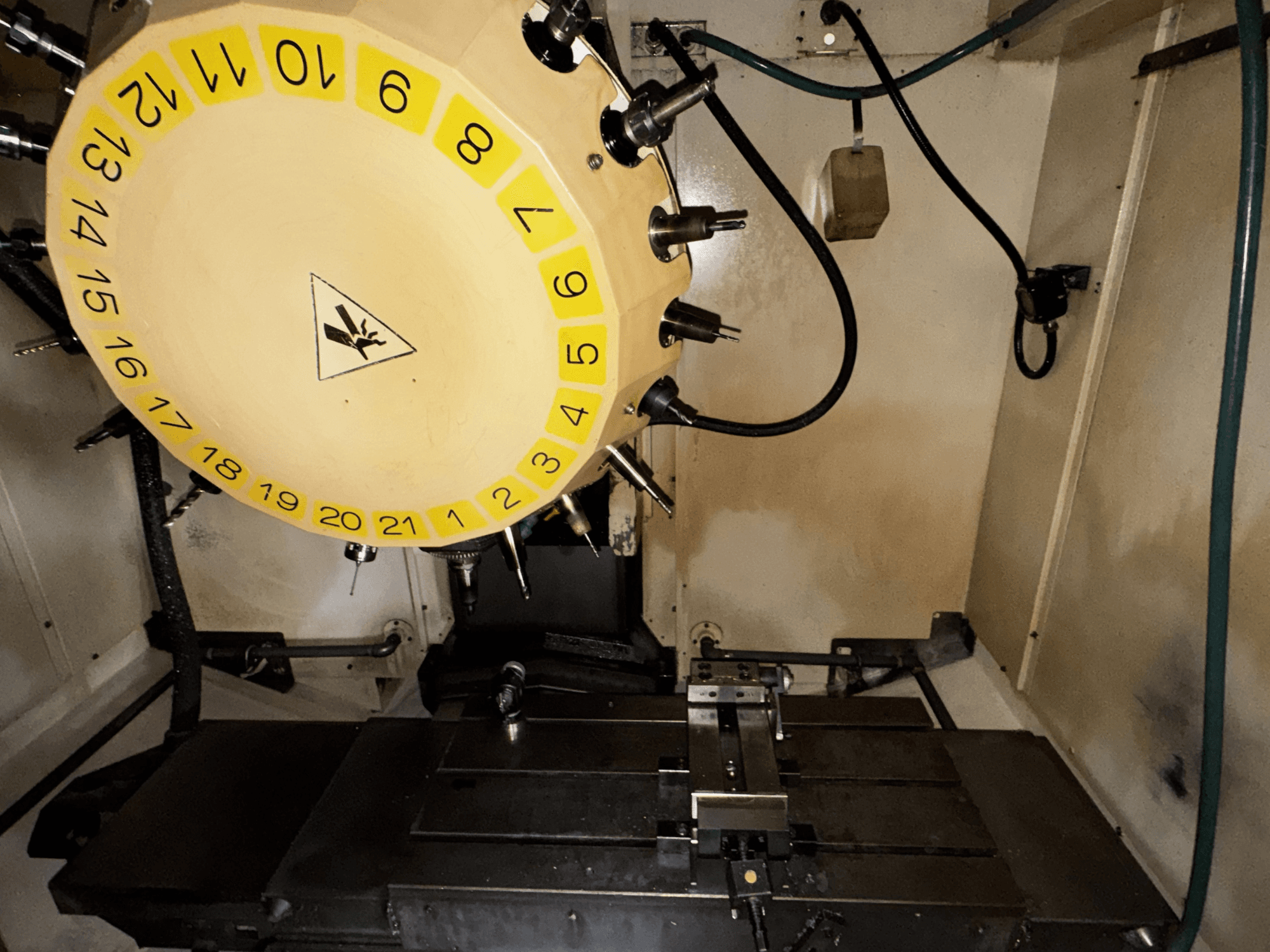 FANUC Robodrill alpha-T21iFL -pystytyöstökeskuksen sisäkuva, jossa työkalukaruselli ja työstöpöytä näkyvissä.
