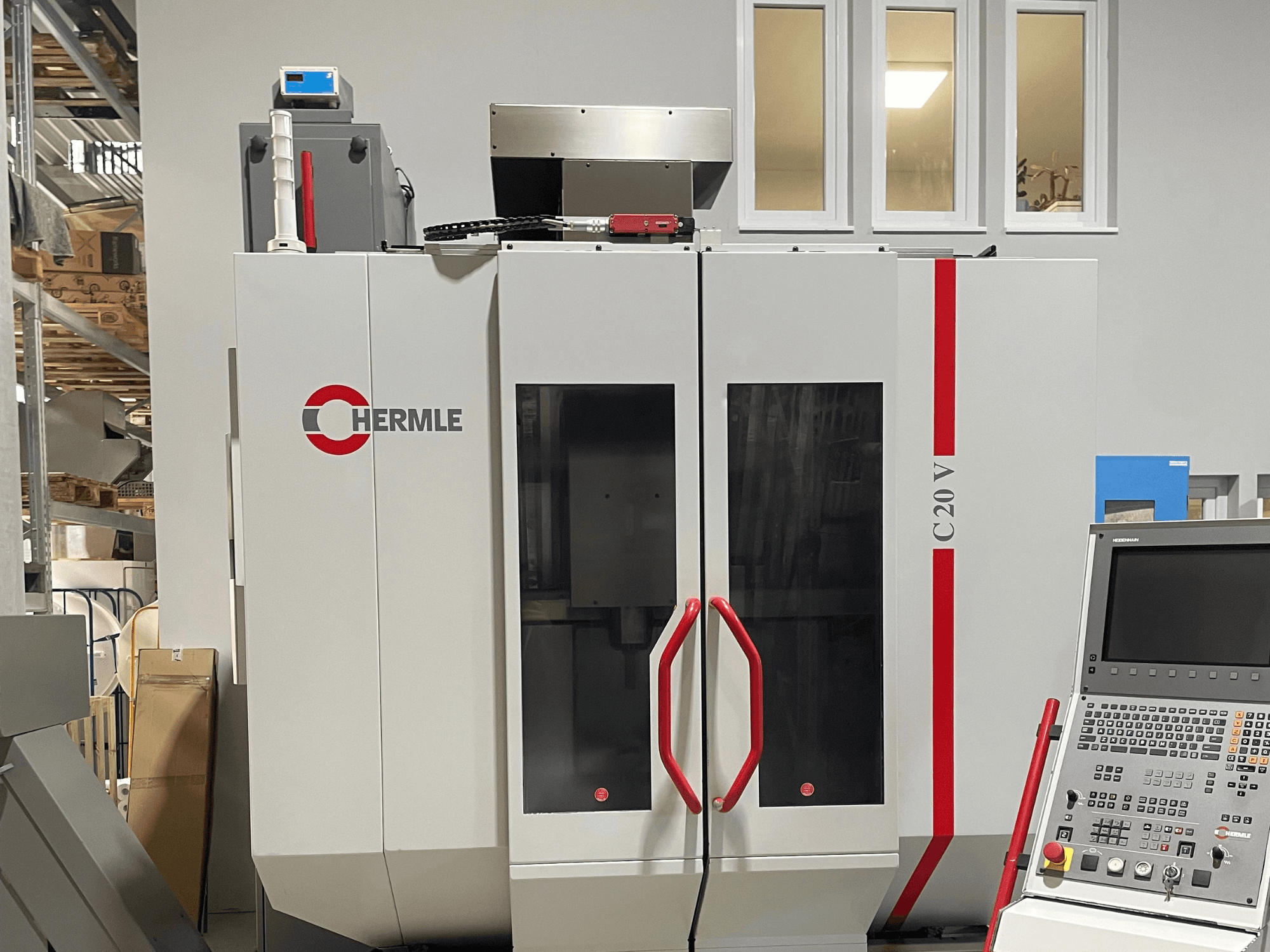 Chermle C20 V CNC-kone, etukuva, jossa on ohjauspaneeli ja punaiset kahvat; teollinen muotoilu ja suuret lasiovet.