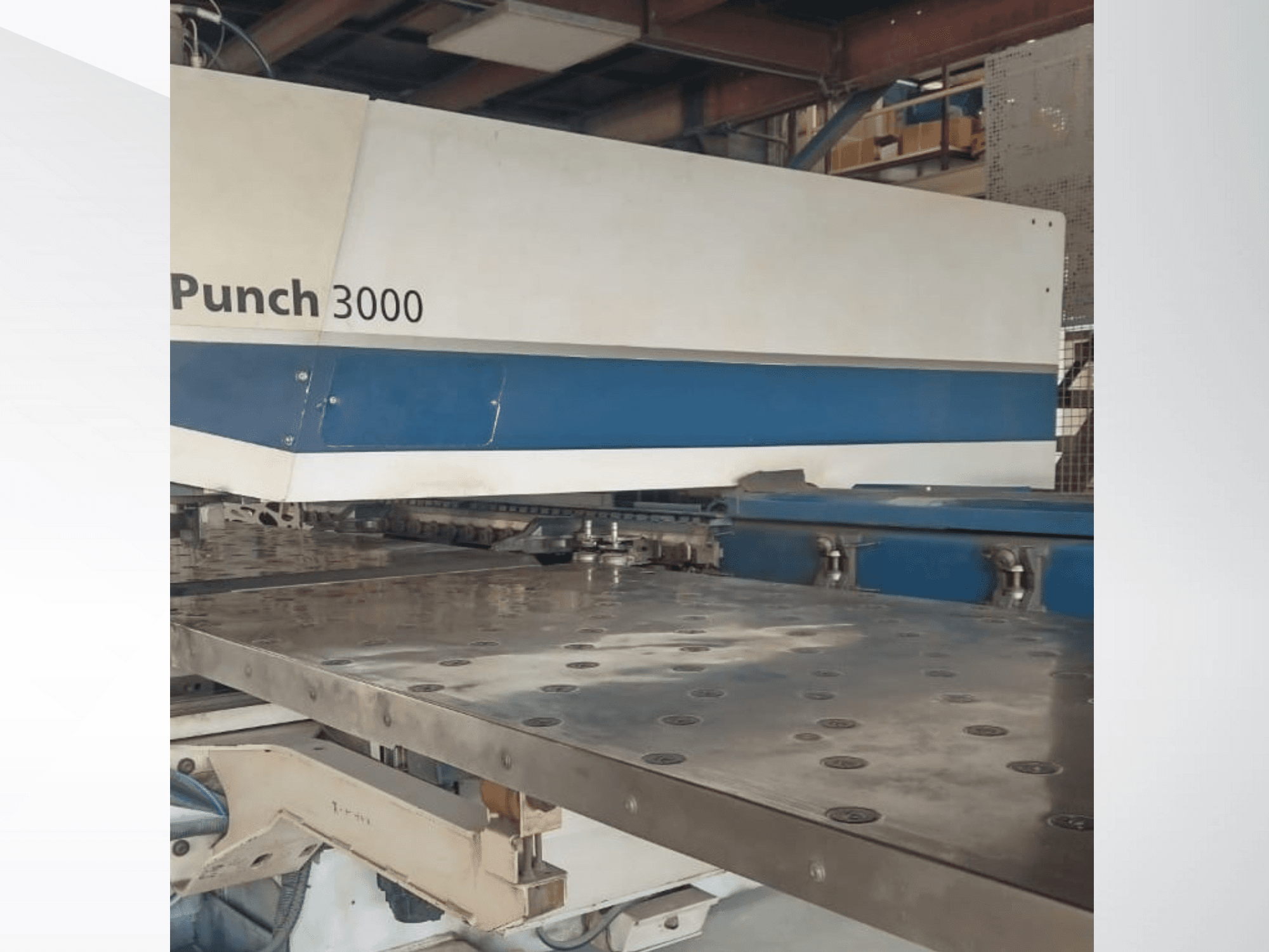 Punch 3000 -kone työpajassa, etukuva, jossa näkyy suuri, tasainen metallipinta, jossa on useita reikiä.