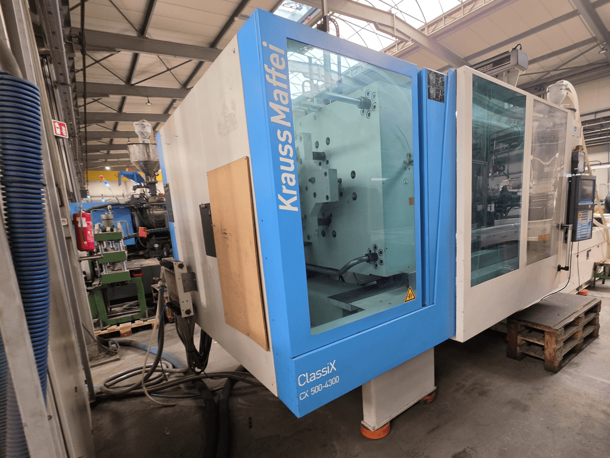 Krauss Maffei 500-4300 CX hydraulinen ruiskuvalukone, sivukuva, jossa näkyy ohjauspaneeli ja käyttöosat.