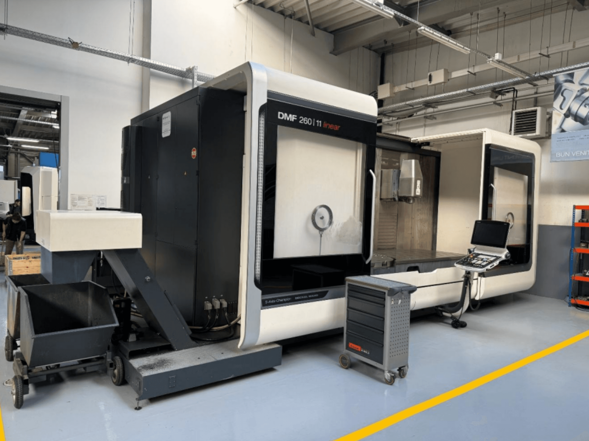 DMG MORI DMF 260 -linjajyrsin edestä kuvattuna, työkalun ohjauspaneeli ja siirrettävä työkaluvaunu vieressä.