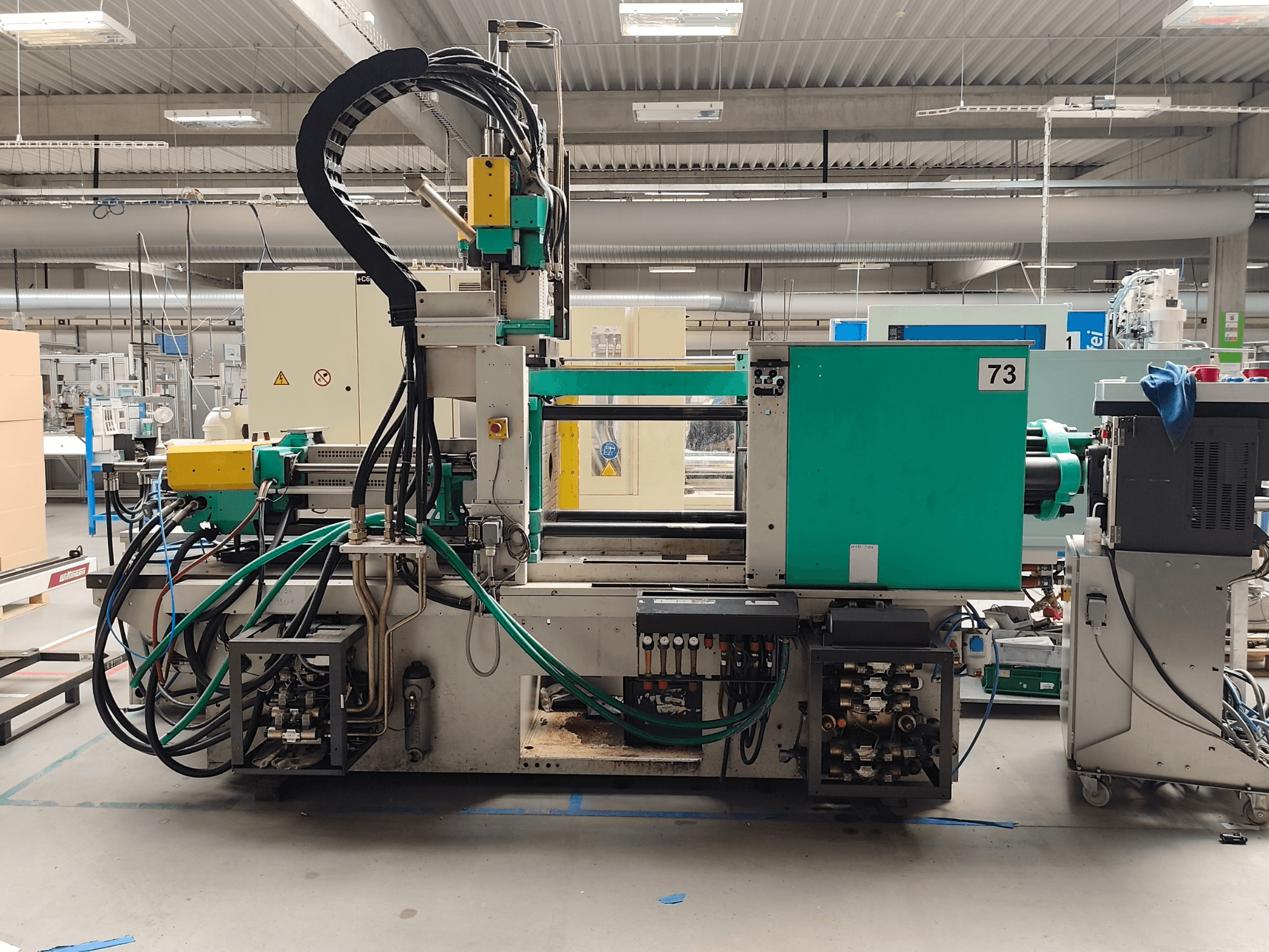 Hydraulinen ruiskuvalukone, Arburg 420 C 1000-150/60, sivukuva, jossa näkyvät hydrauliikkaliitännät ja käyttölaitteet.
