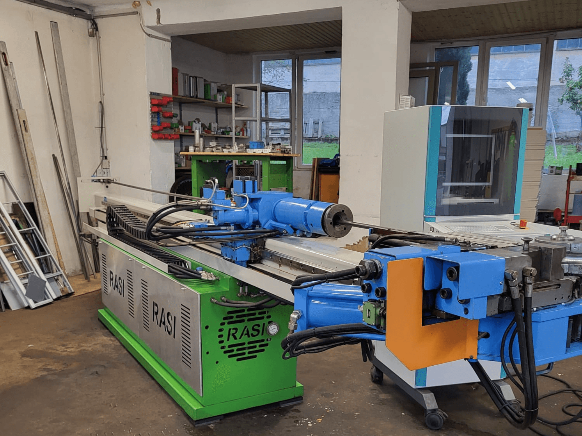 Rasi S 80.6 L G-V3C50 työstökone työpajalla, sivukuva, jossa näkyy siniset ja vihreät osat ja ohjauspaneeli.