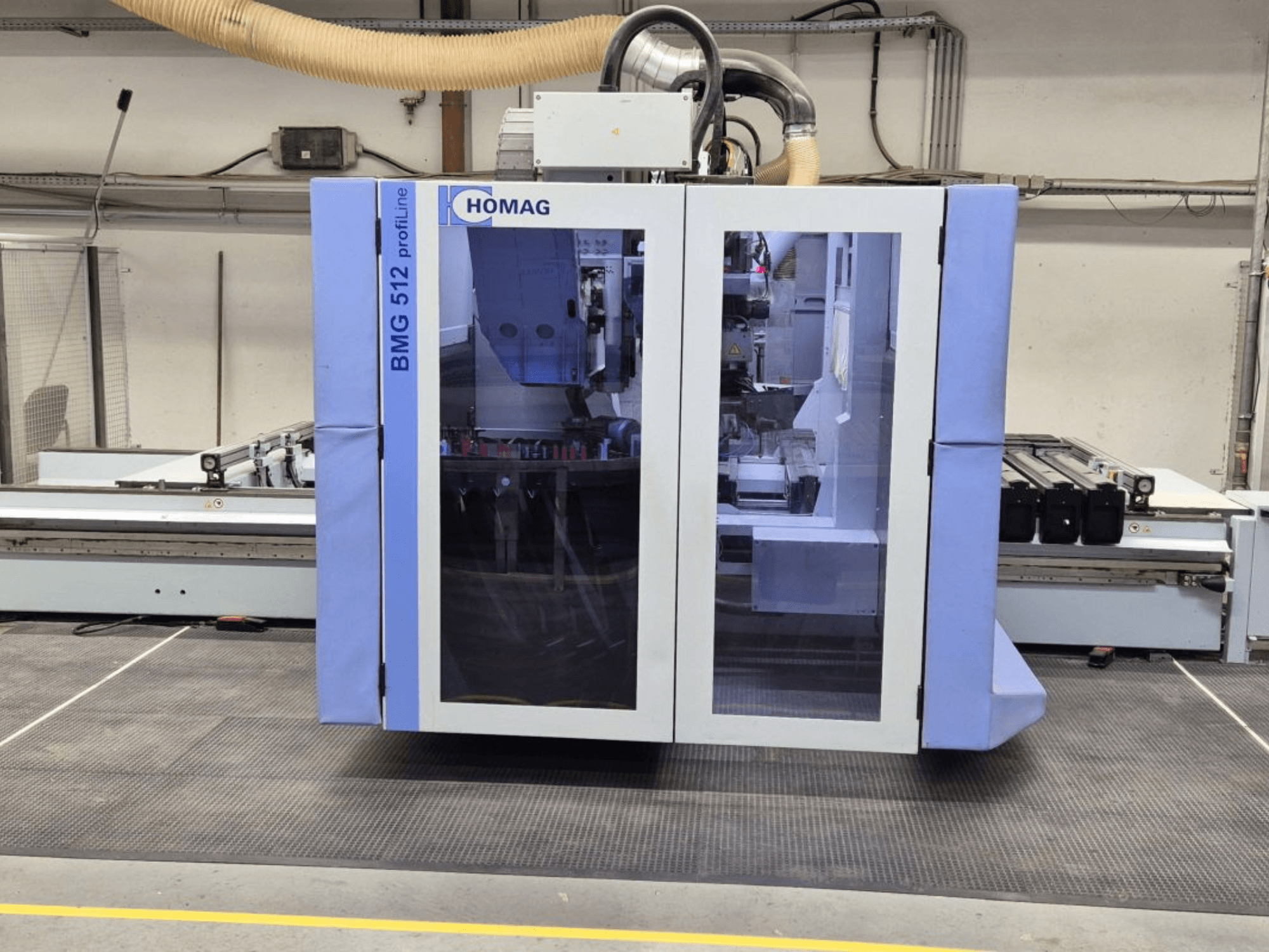 HOMAG BMG 512 ProfiLine CNC-kone, etukuva, jossa on lasipaneeli, tarkkuustyökalut näkyvissä ja teollisuusympäristö.