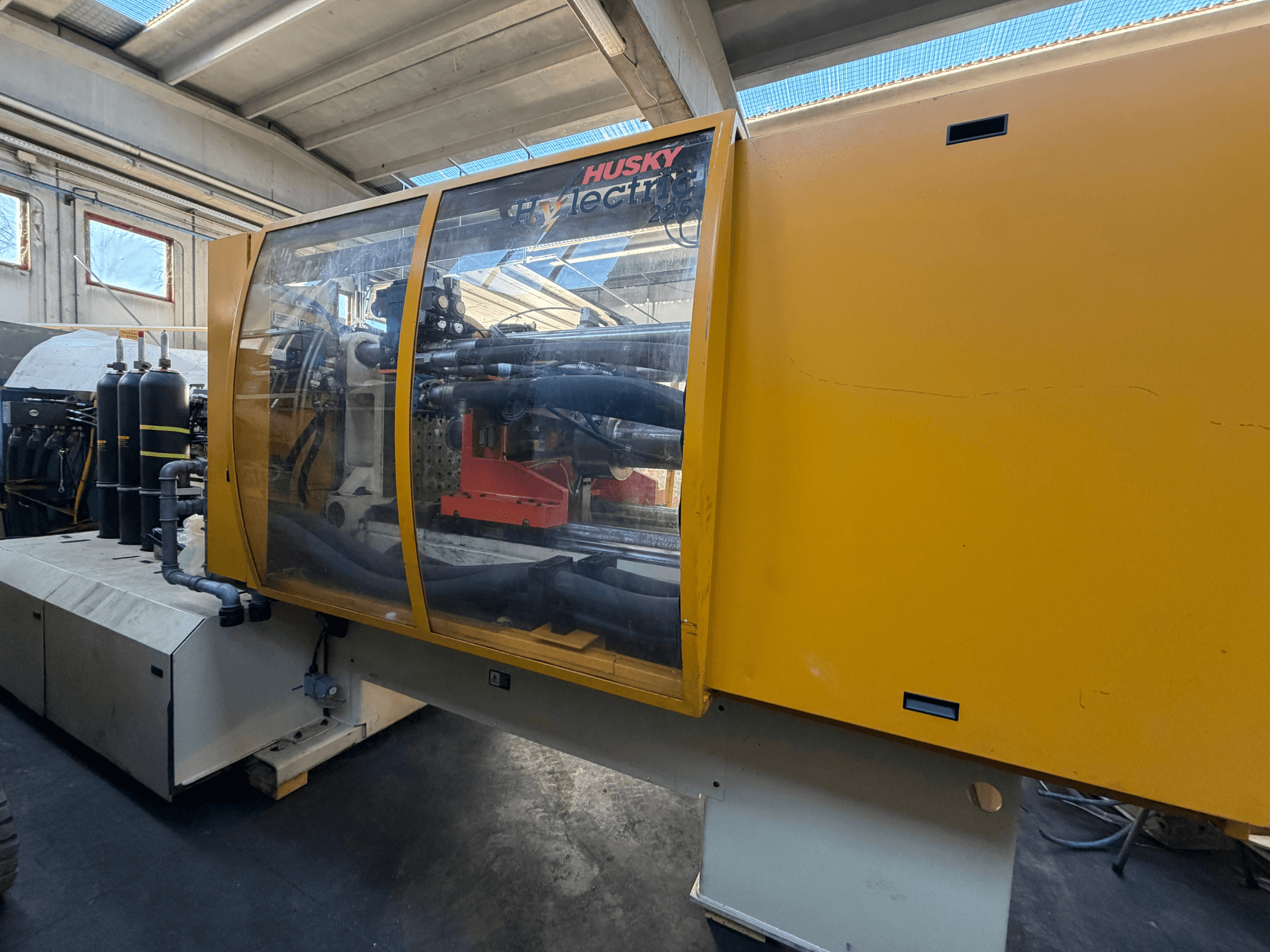Husky HL225 RS65 sähköinen ruiskuvalukone, etukuva, jossa keltainen kotelo, näkyvä ohjauspaneeli ja hydrauliset komponentit.